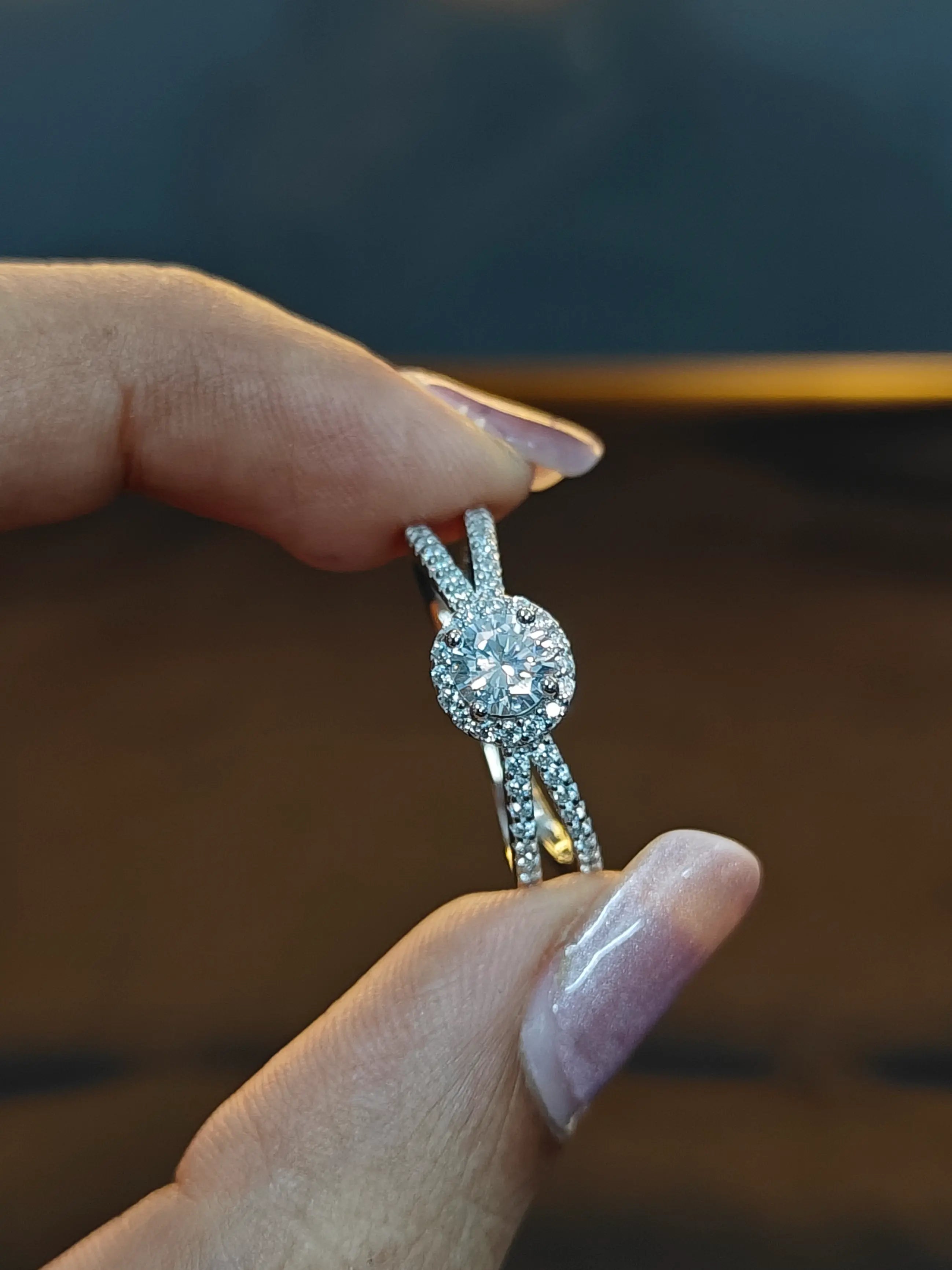 Silver ring with intricate design held by a hand against a blurred background
