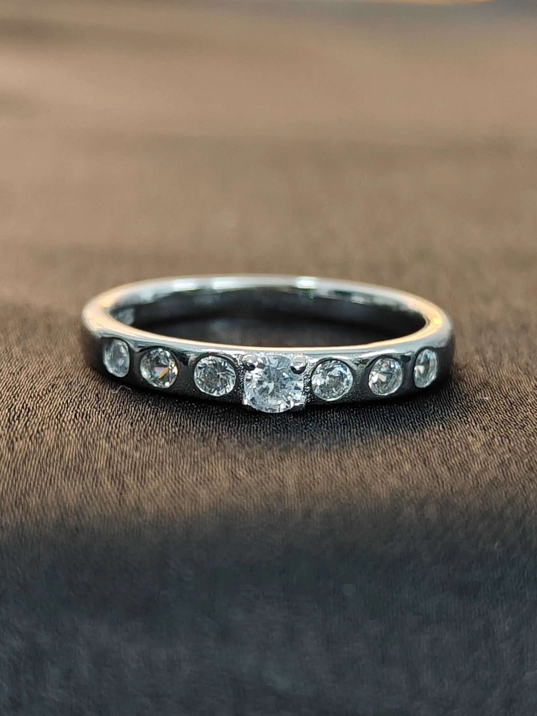 Silver ring with embedded diamonds on a brown fabric background