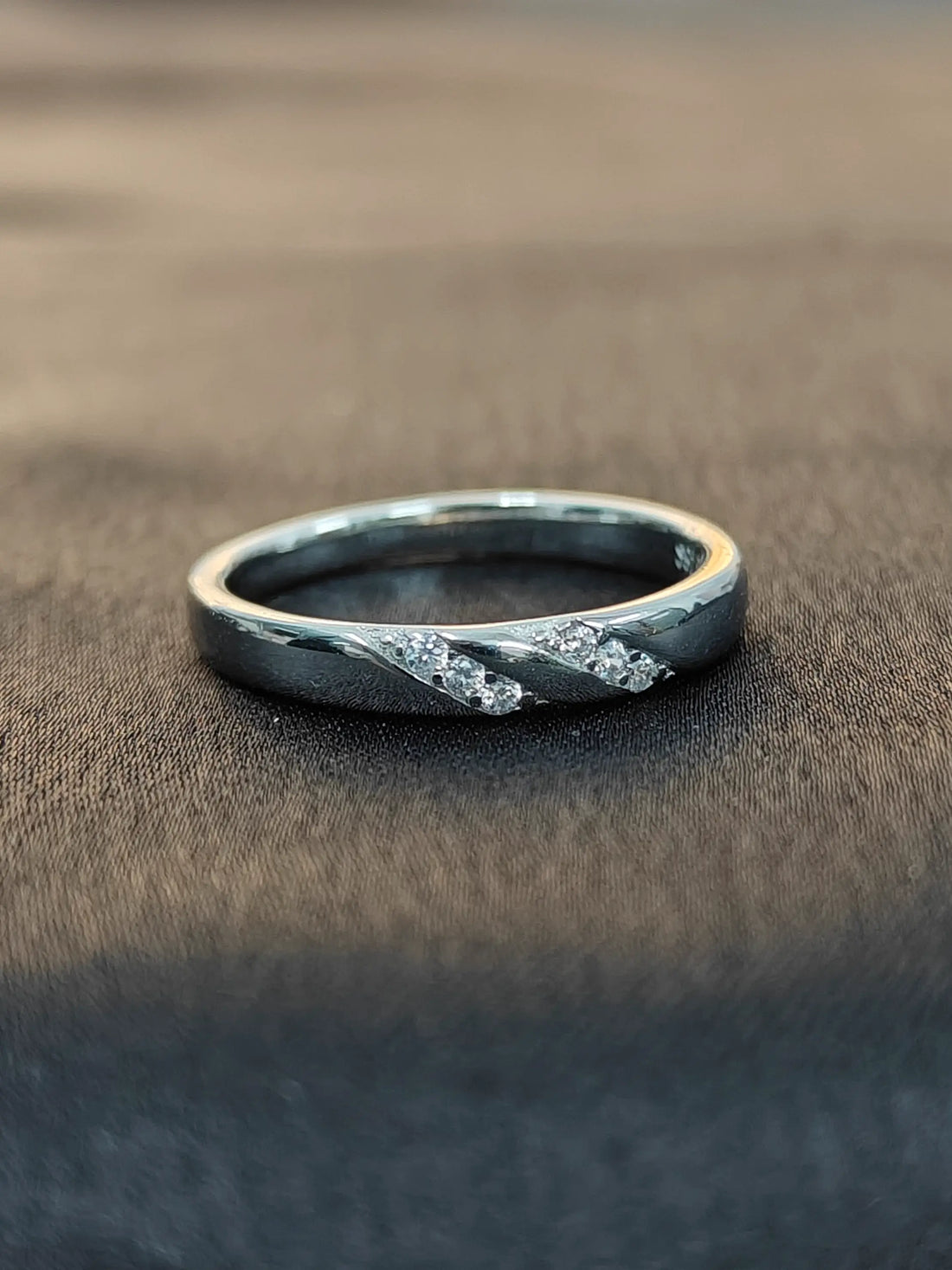 Silver ring with embedded stones on a brown fabric background