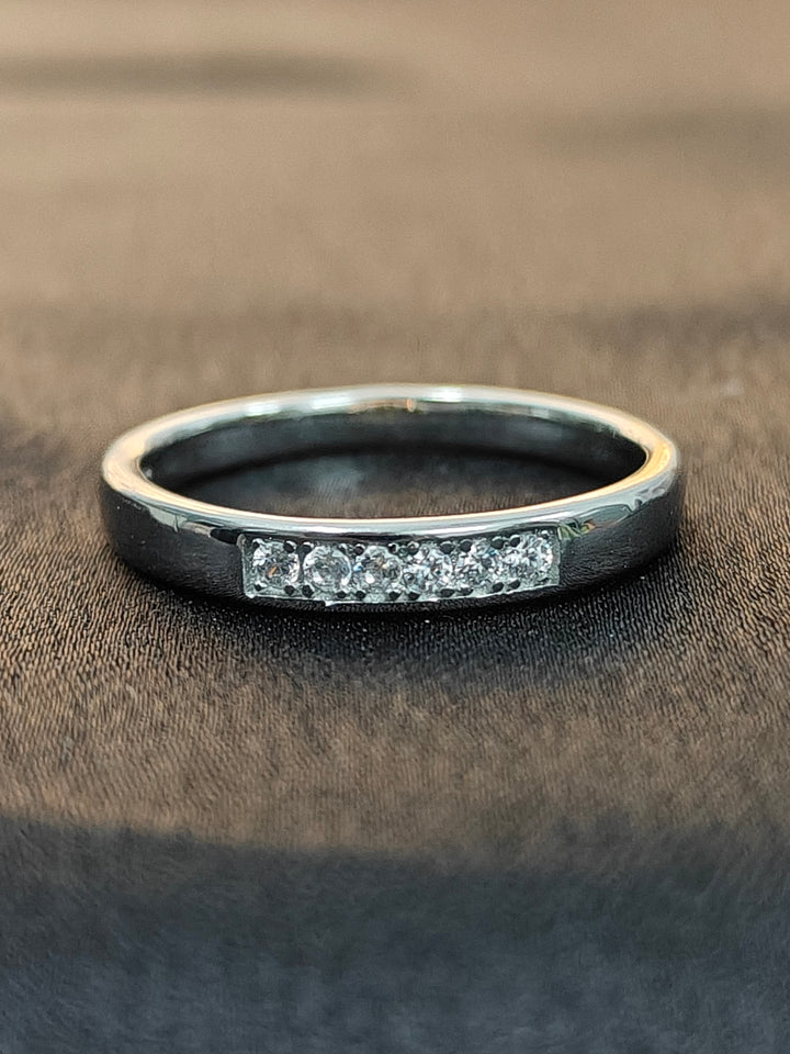 Silver ring with embedded diamonds on a brown fabric background