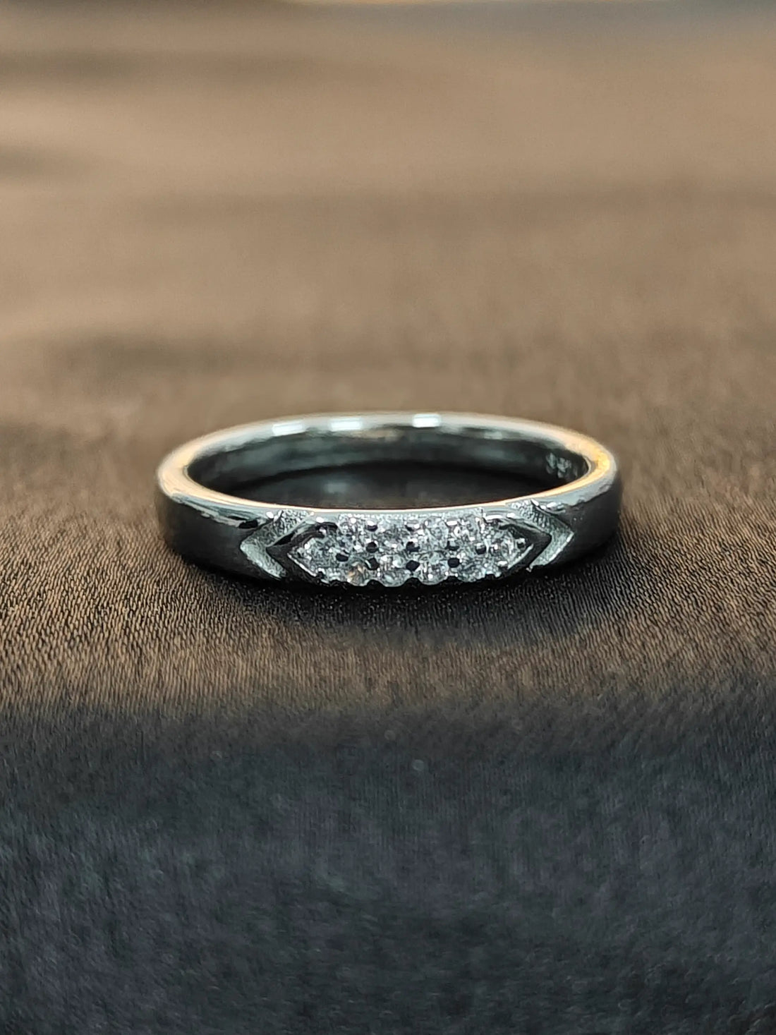 Silver ring with gemstones on a brown fabric background