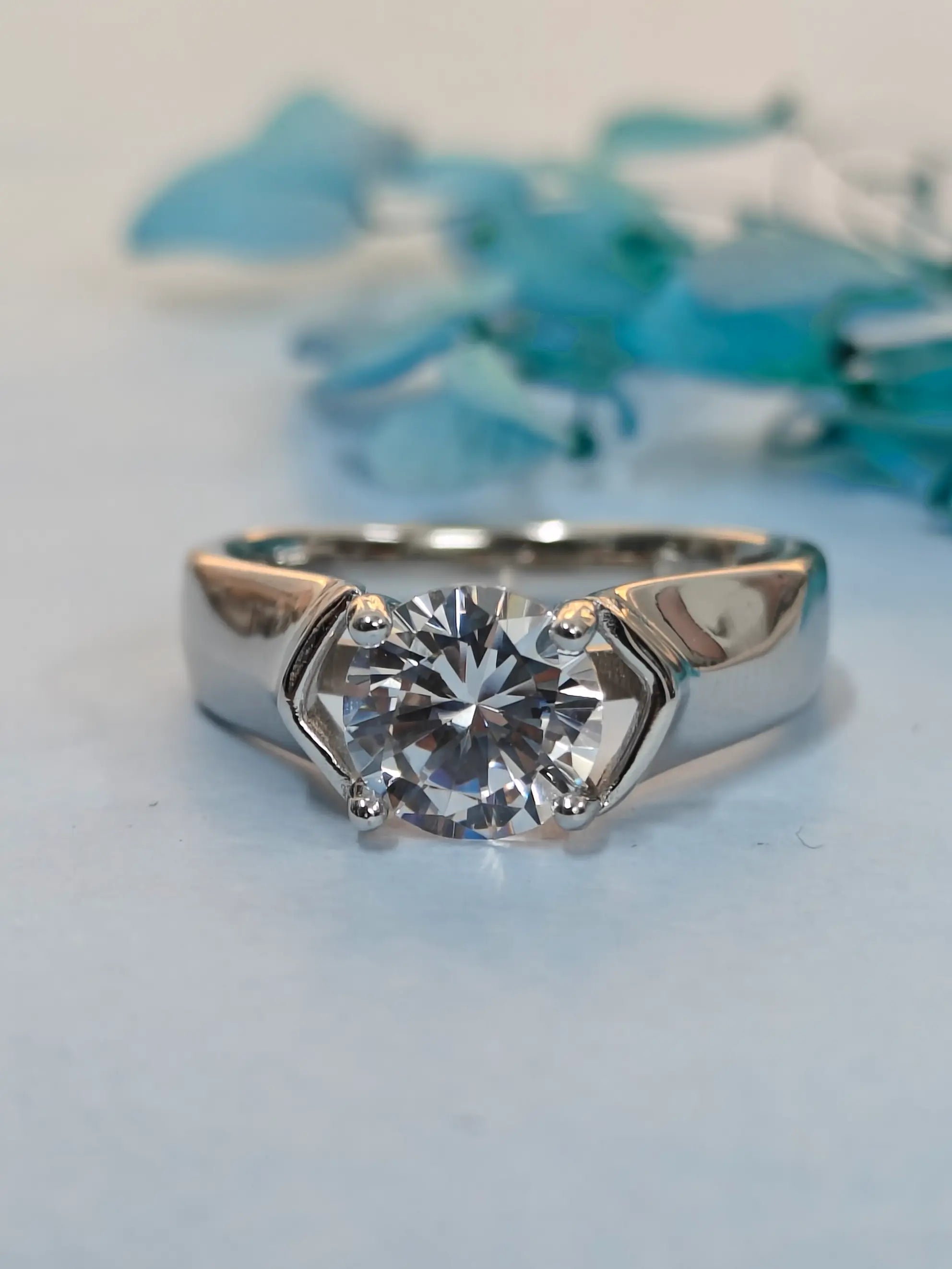 Silver ring with a large diamond on a light blue background