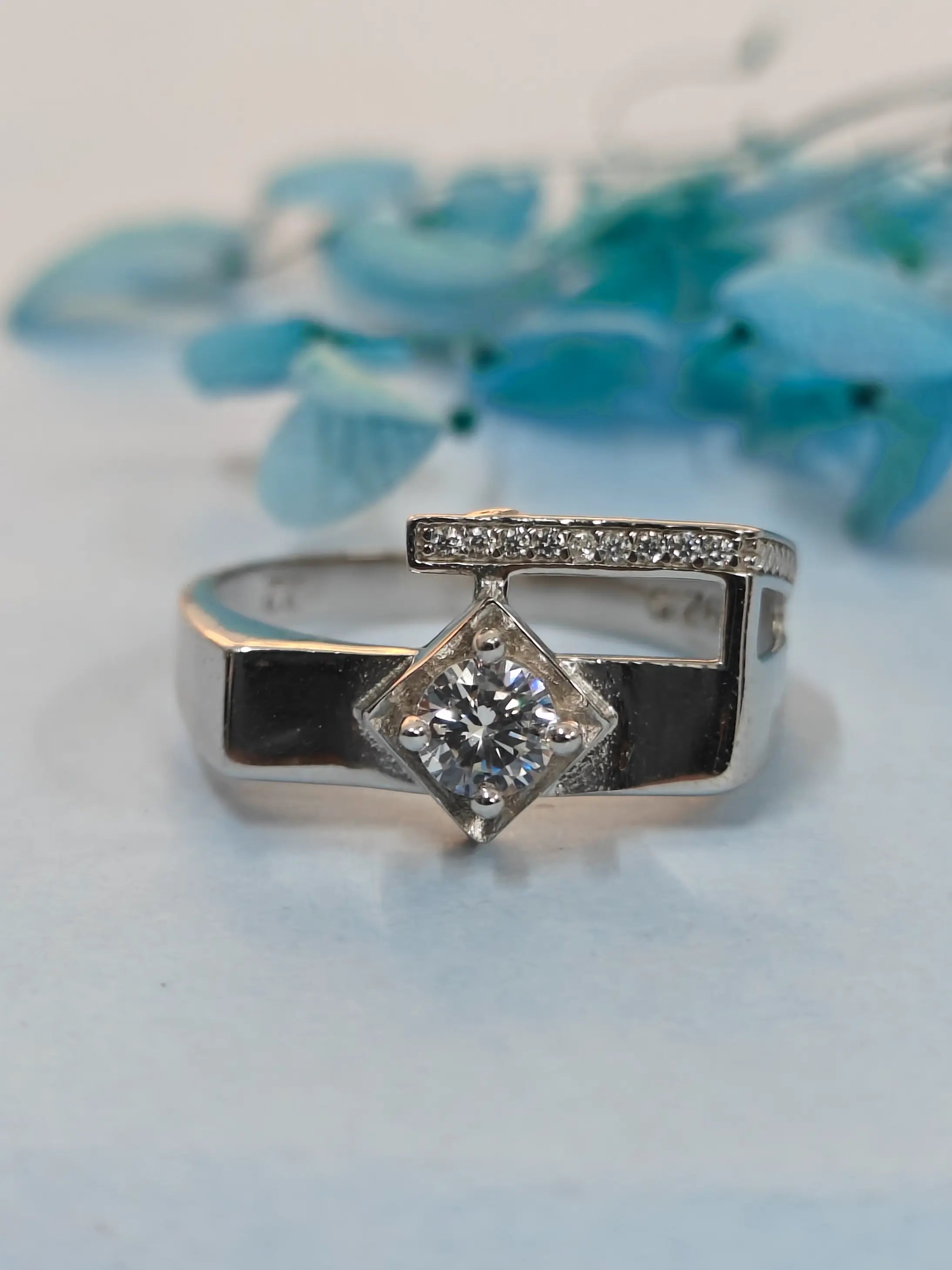 Silver ring with a diamond on a light blue background