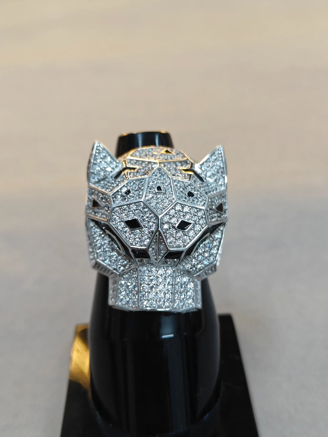 Silver panther head ring with gemstones on a stand against a neutral background