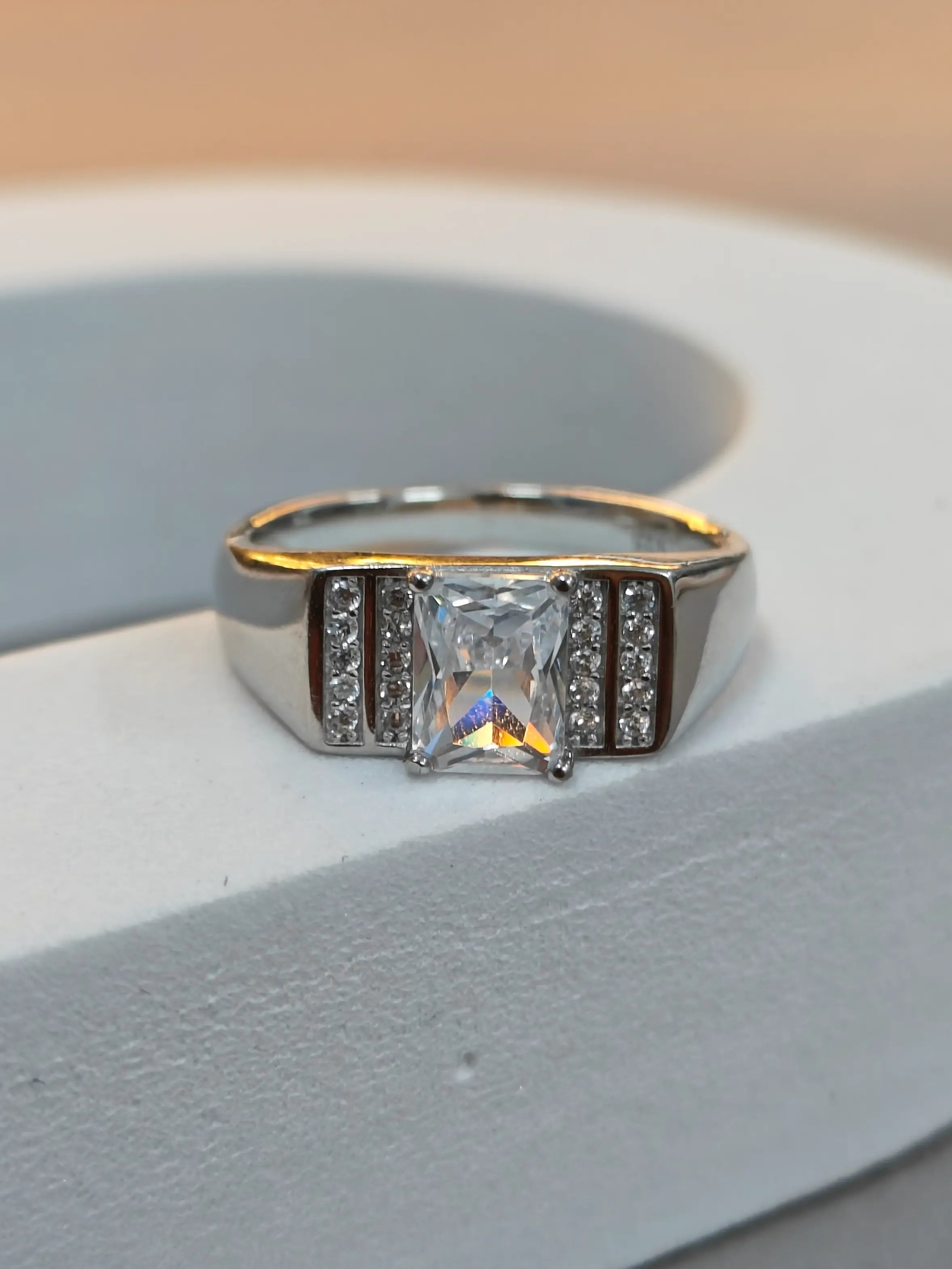 Diamond ring with gold and silver band on a light gray surface