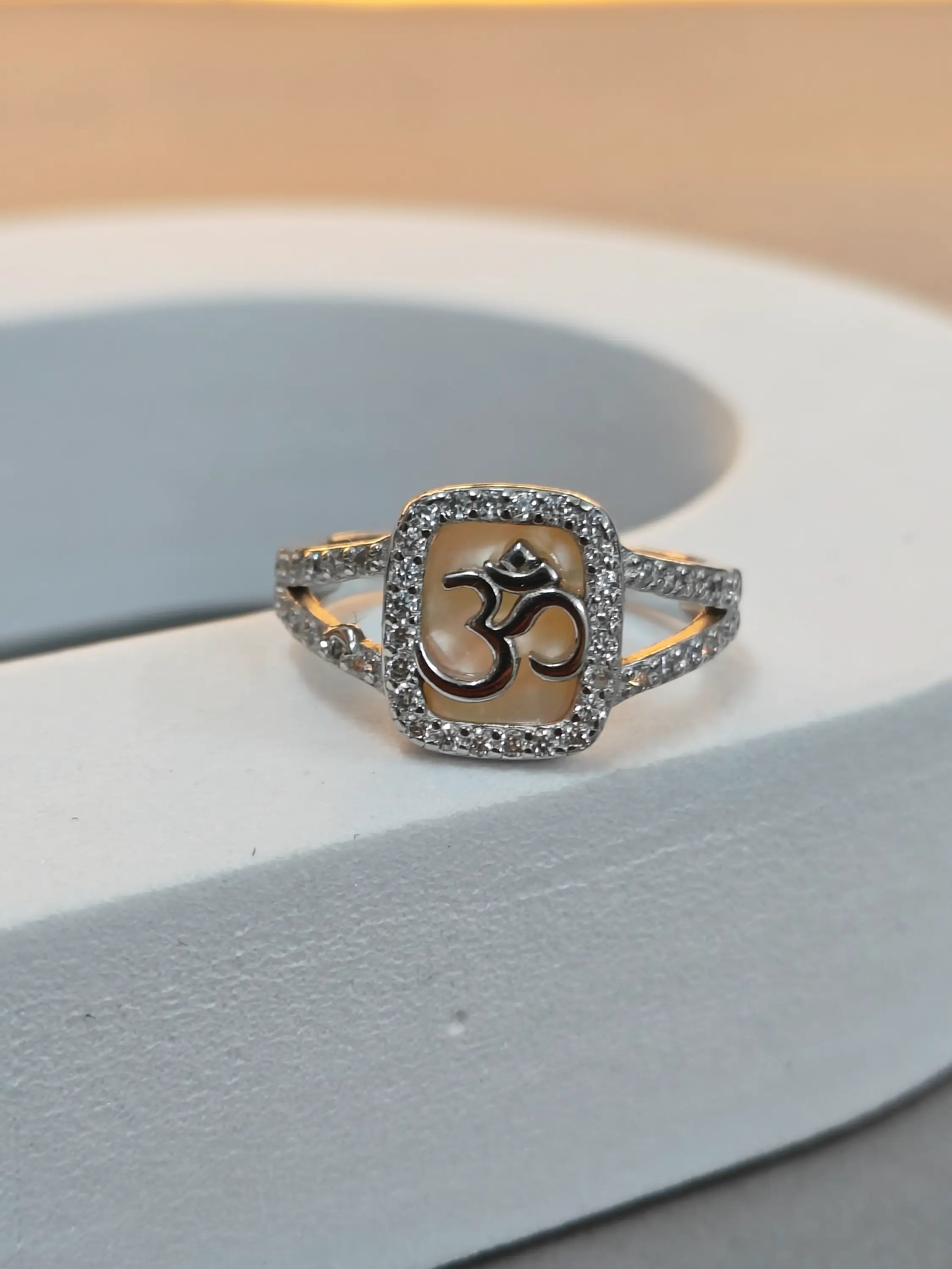 Silver ring with Om symbol on a light gray background