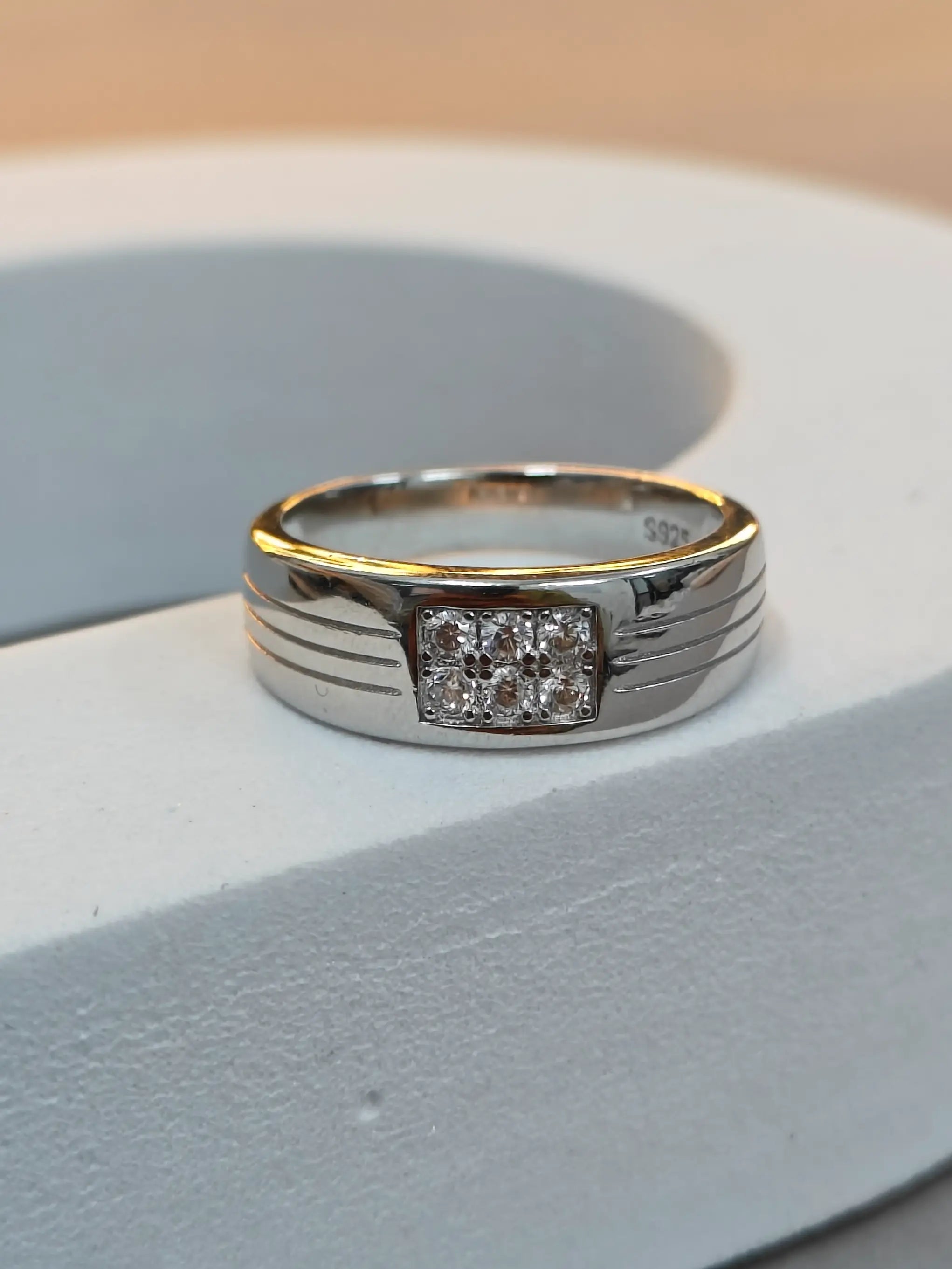 Silver ring with a diamond on a light gray surface