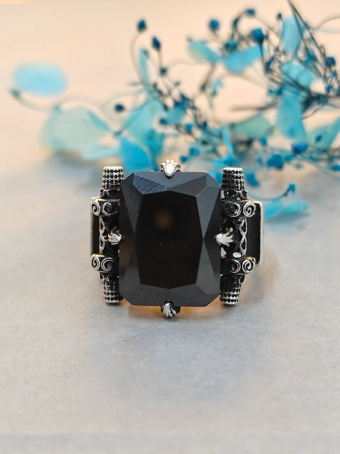 Ring with a black gemstone and silver accents on a light background