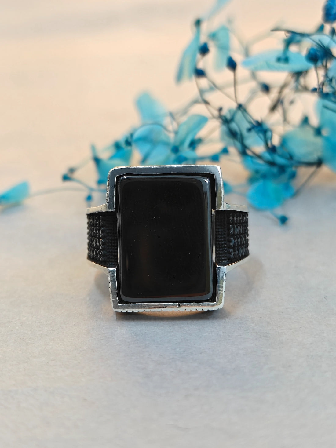 Black square object with metal frame on a light background with blue flowers