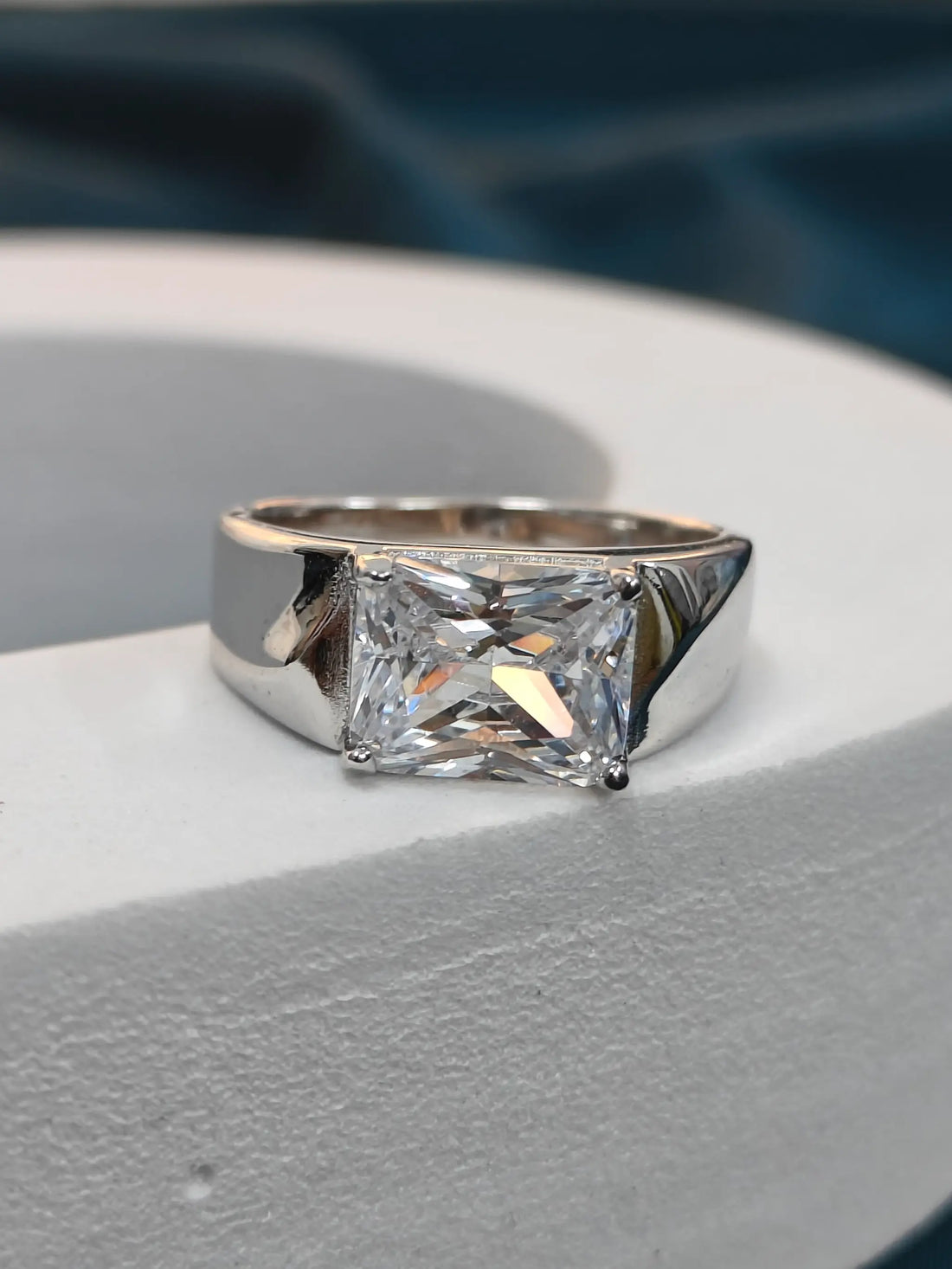 Silver ring with a large diamond on a gray surface