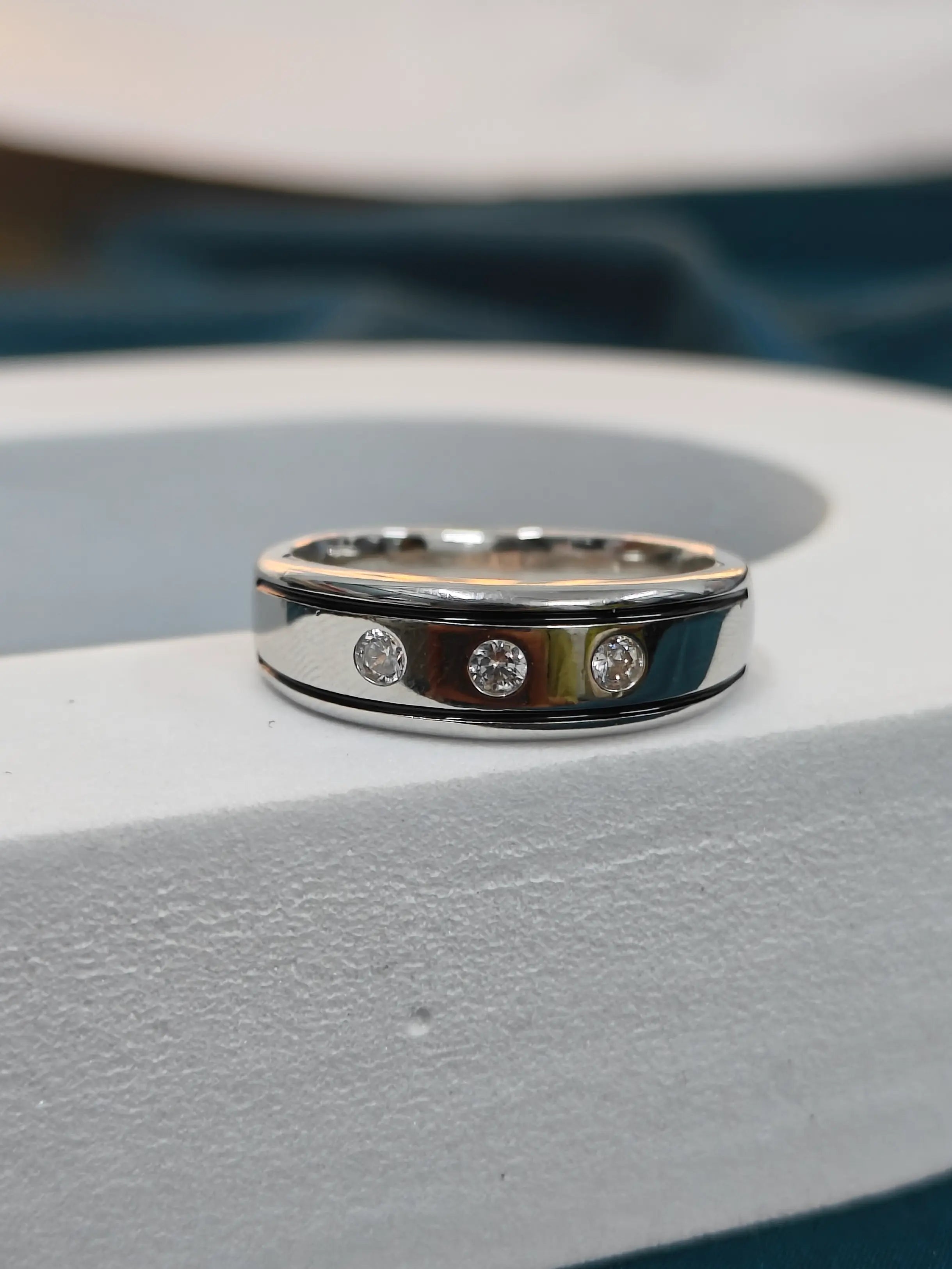 Silver ring with three diamonds on a light gray surface