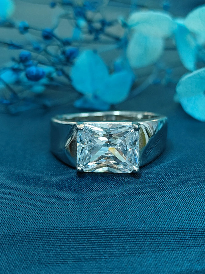 Silver ring with a large diamond on a blue fabric background