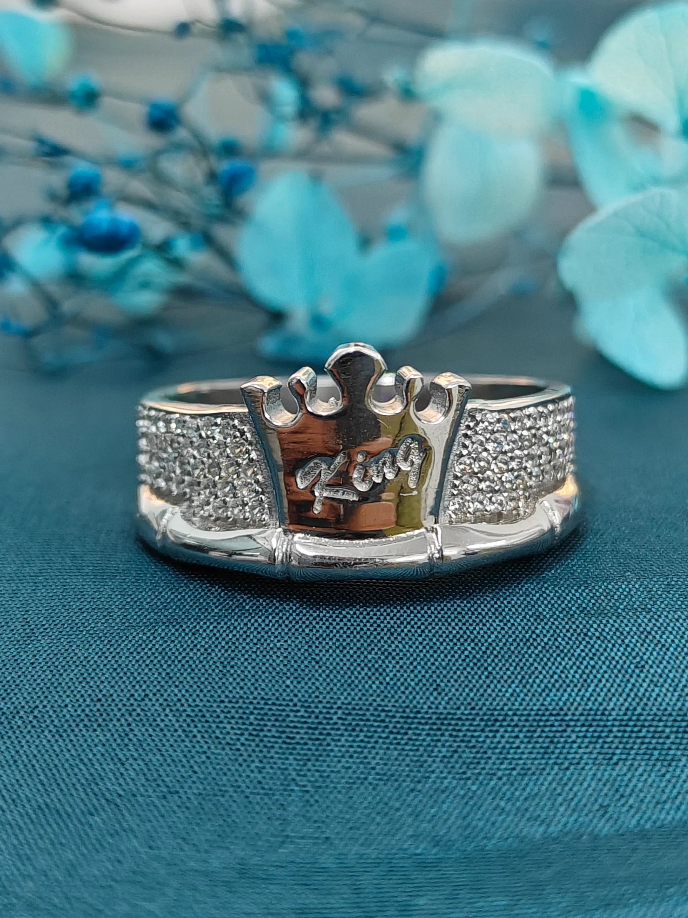 Silver ring with 'King' engraving on a blue fabric background