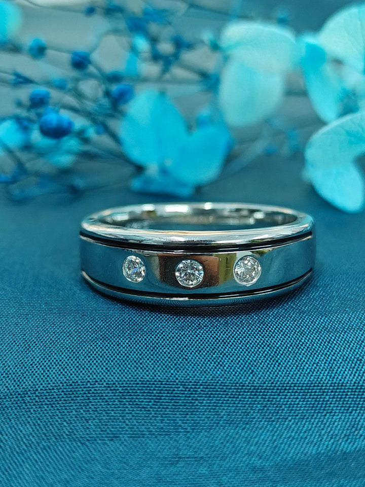 Silver ring with embedded diamonds on a blue fabric background with blue flowers.