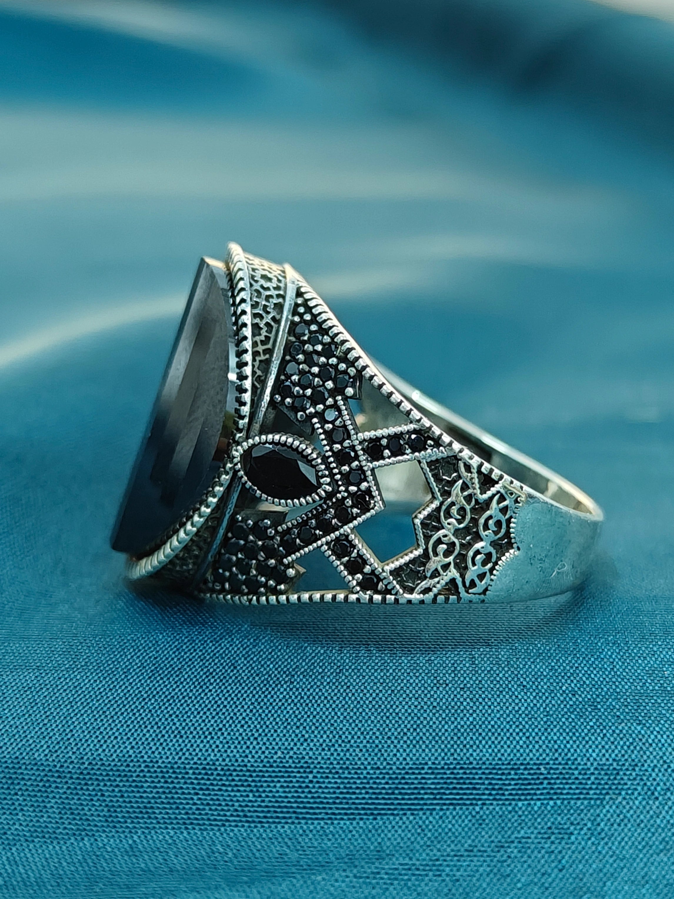 Decorative silver ring with black stone on a blue fabric background