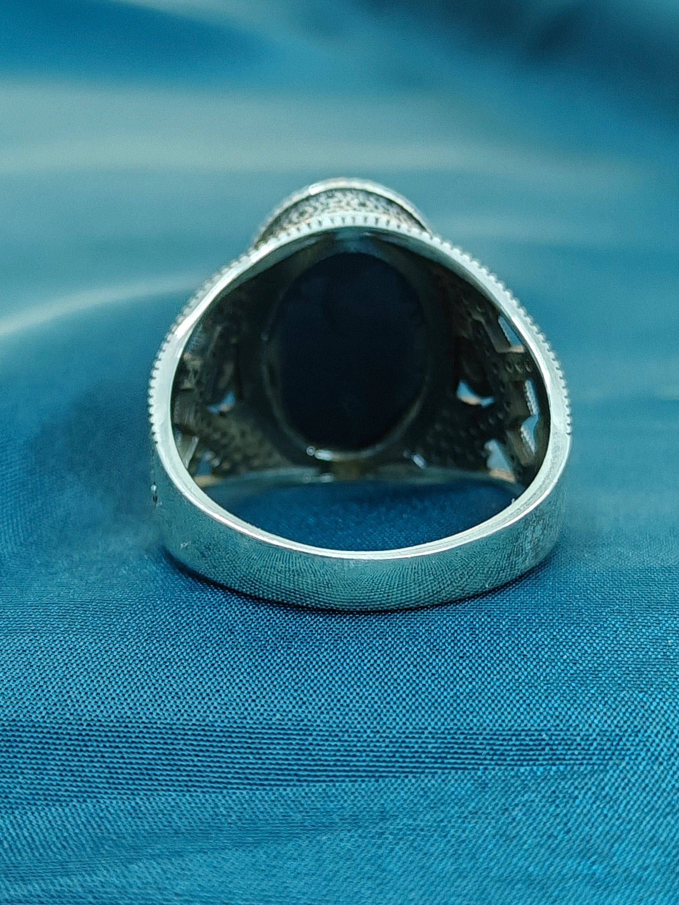 Silver ring with a black stone on a blue fabric background