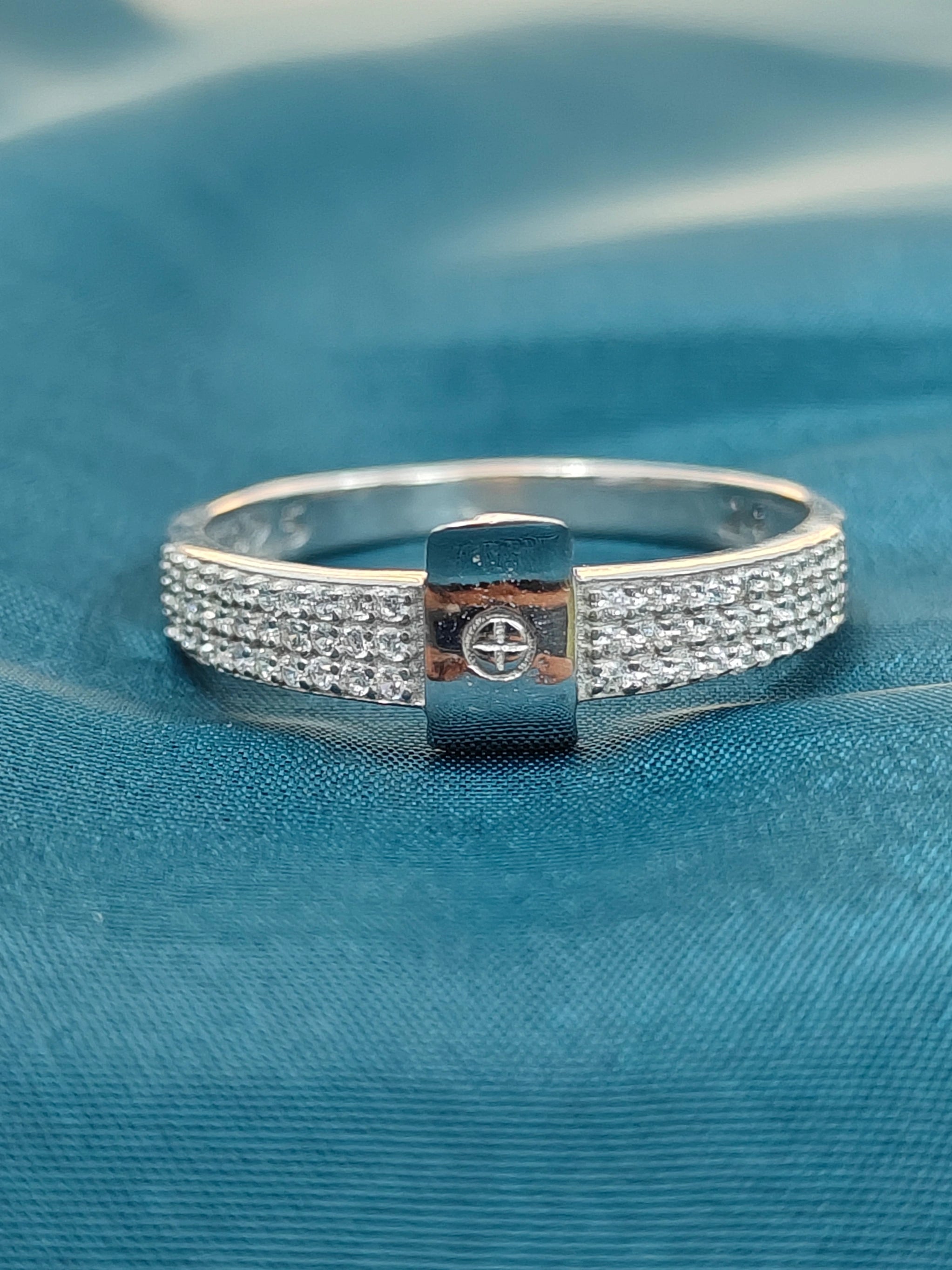 Silver bracelet with a central square design on a blue fabric background