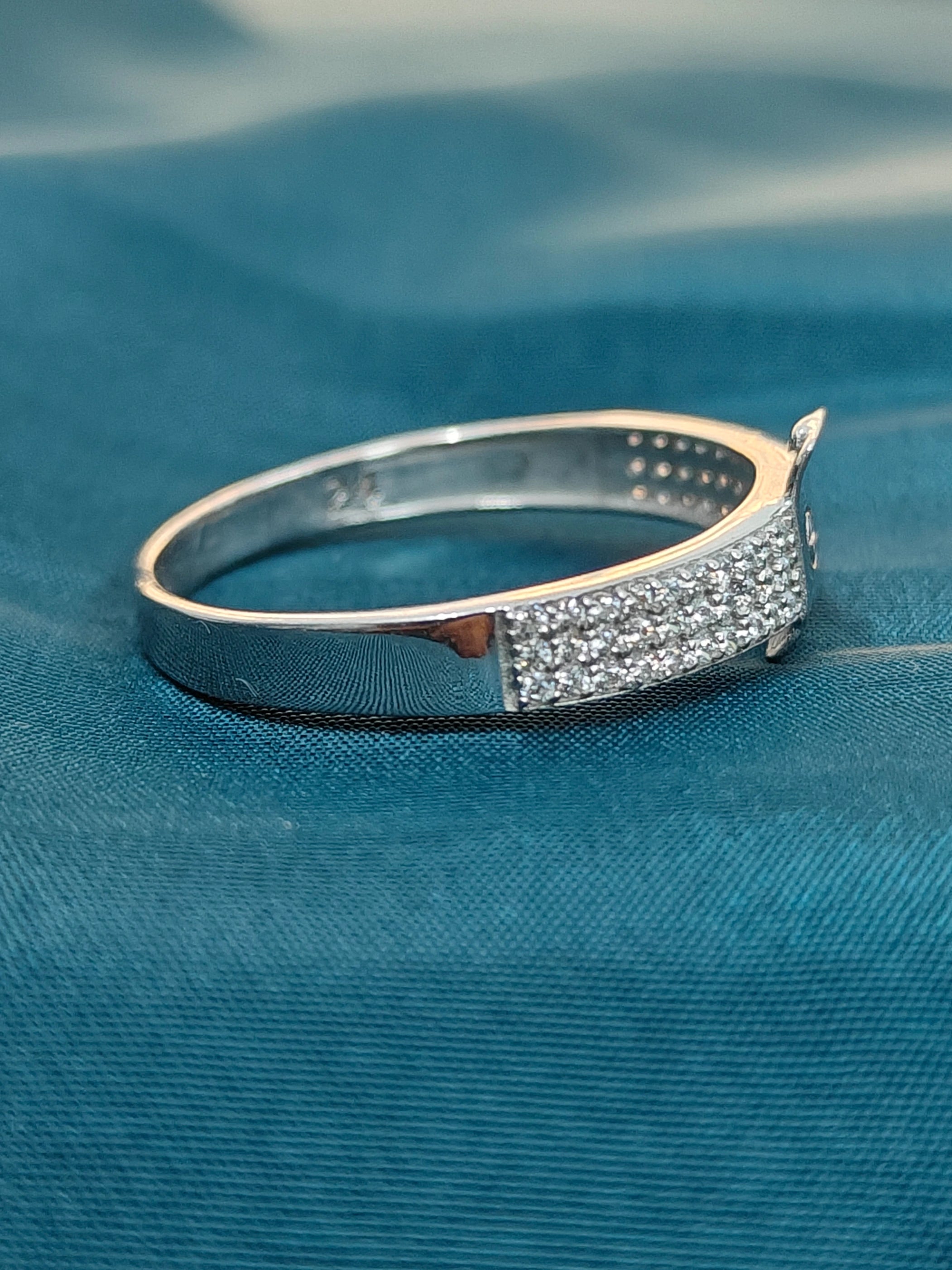 Silver ring with embedded stones on a blue fabric background