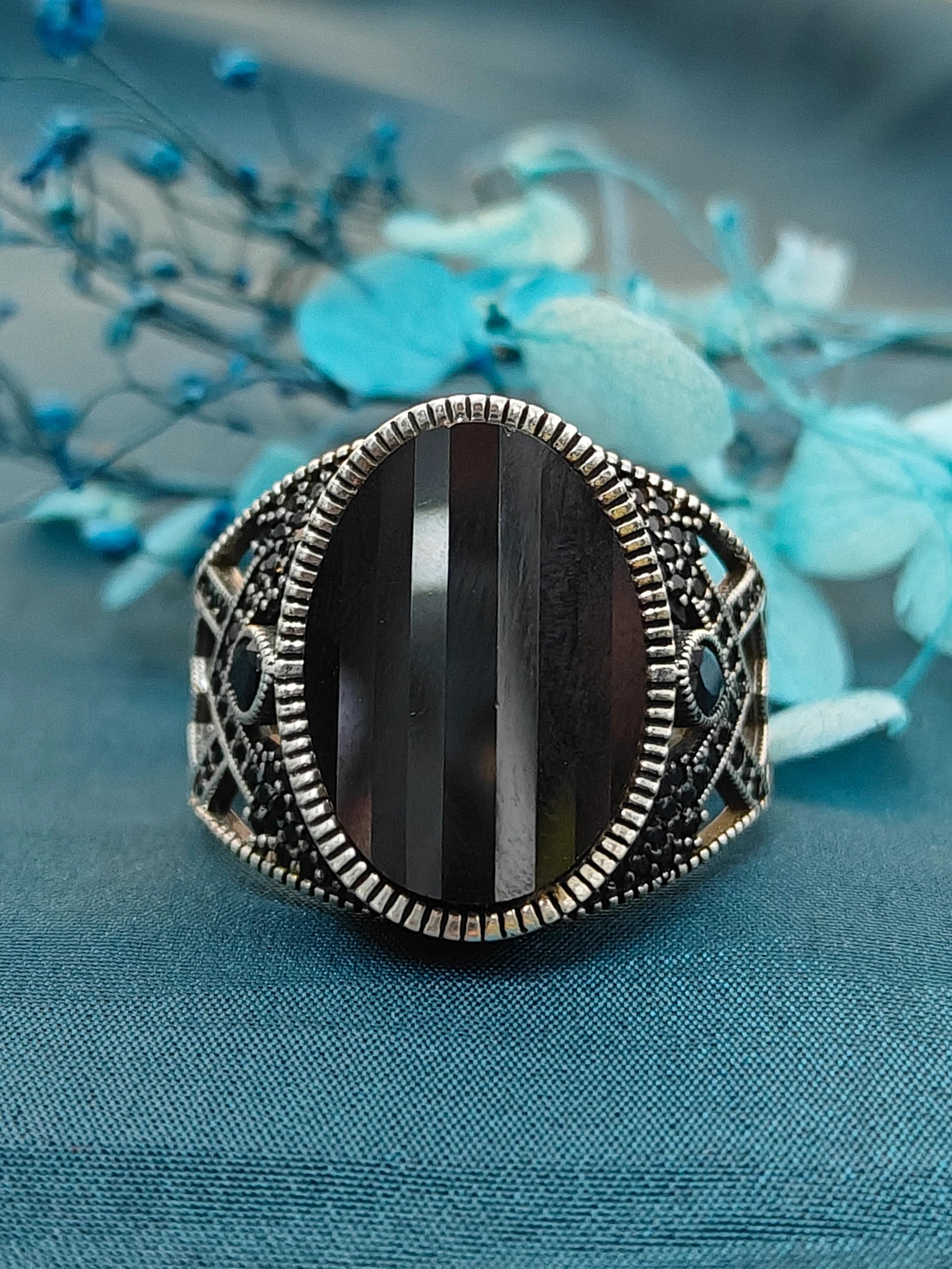 Decorative ring with a black stone on a blue fabric background