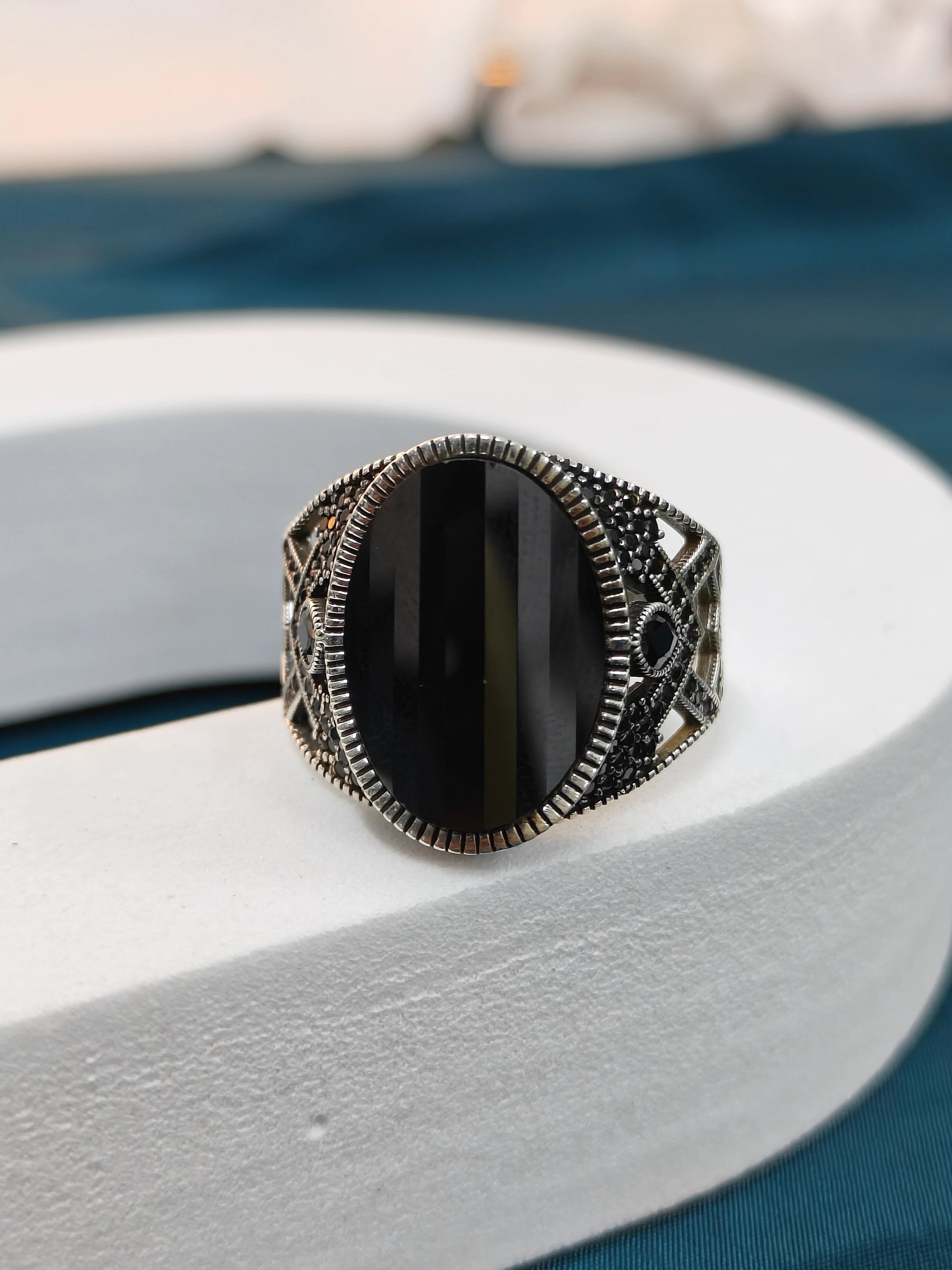 Silver ring with a black stone on a white surface