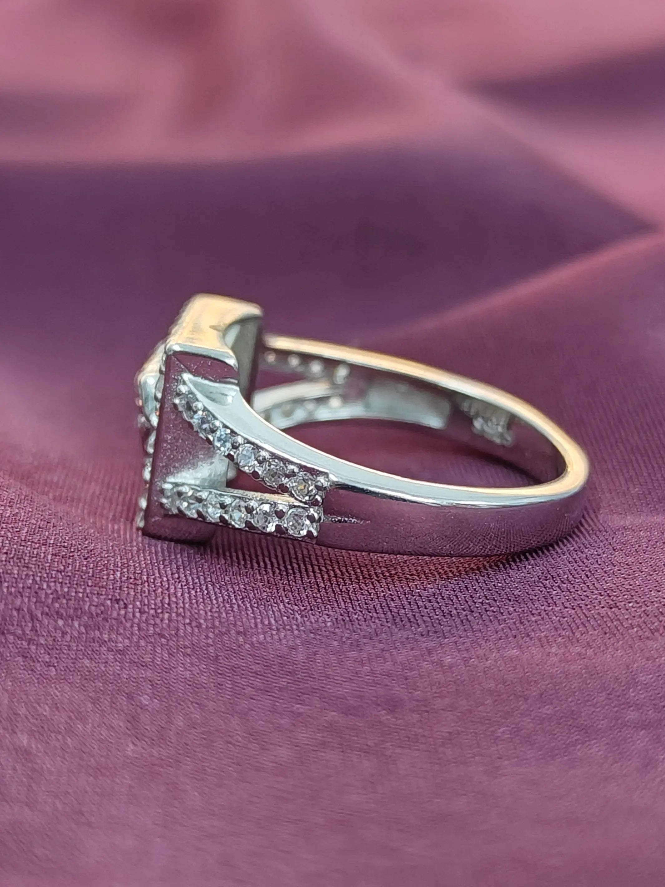 Silver ring with small diamonds on a purple fabric background