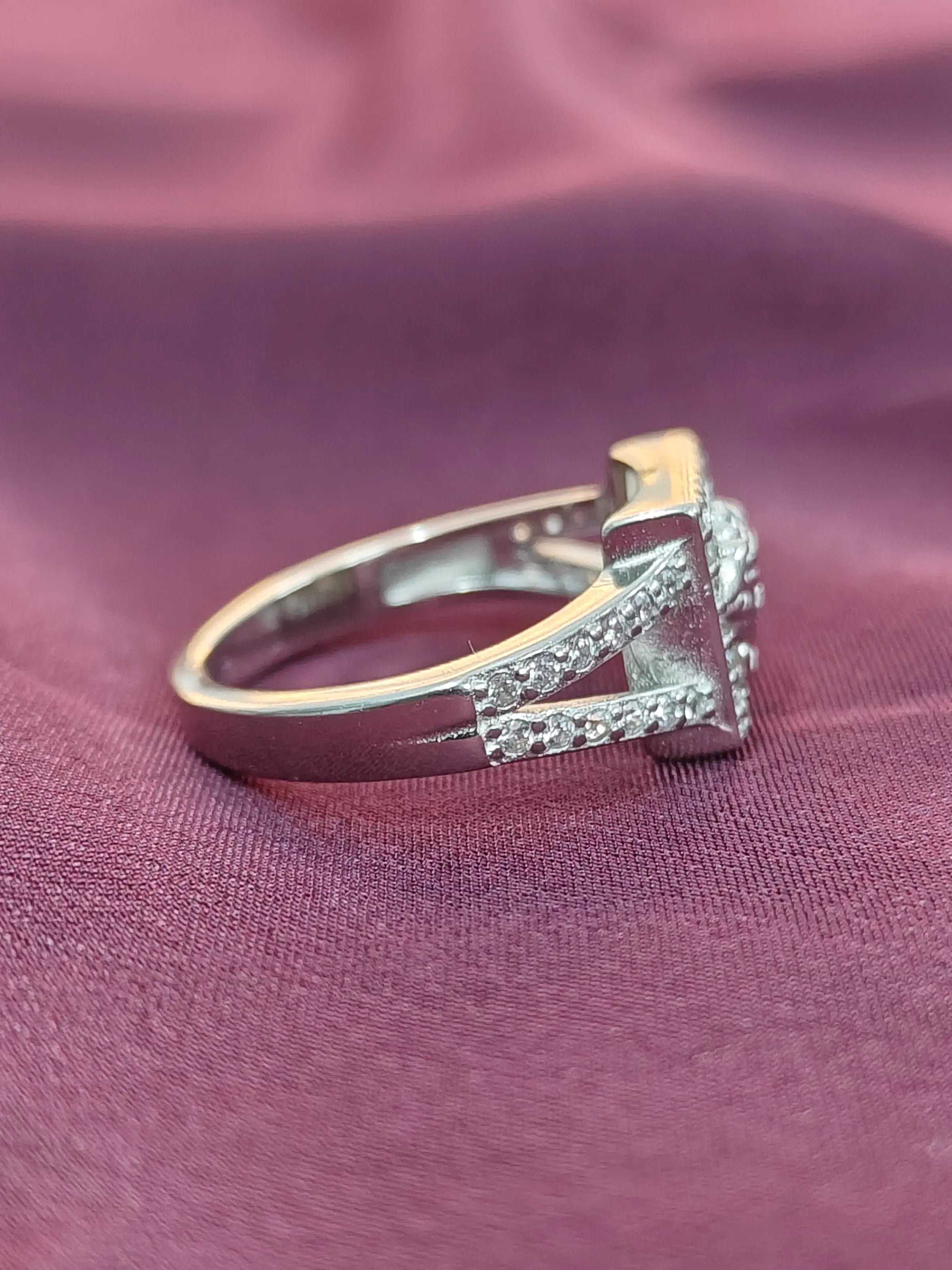 Silver ring with gemstones on a purple fabric background.