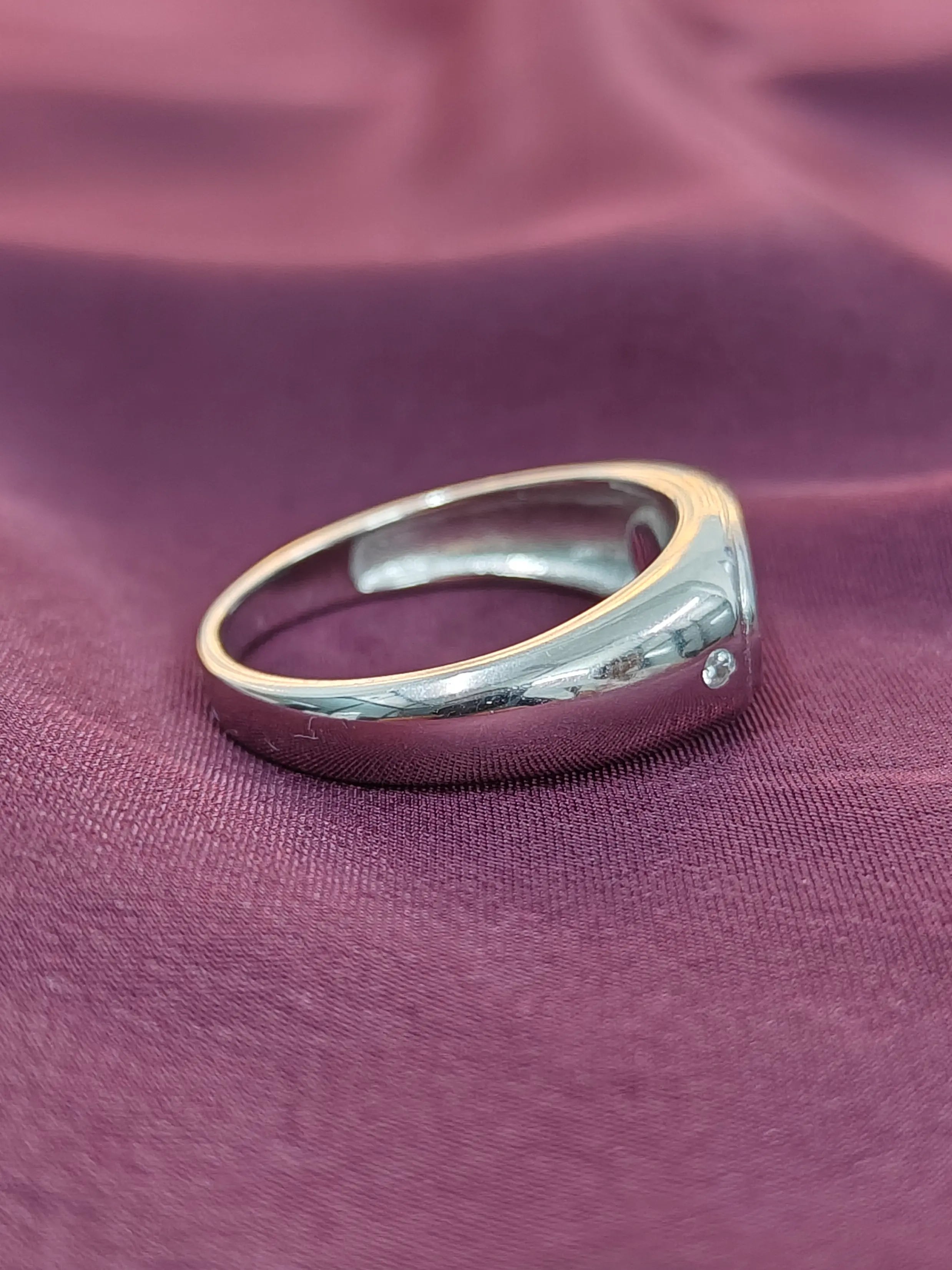 Silver ring with a small diamond on a purple fabric background