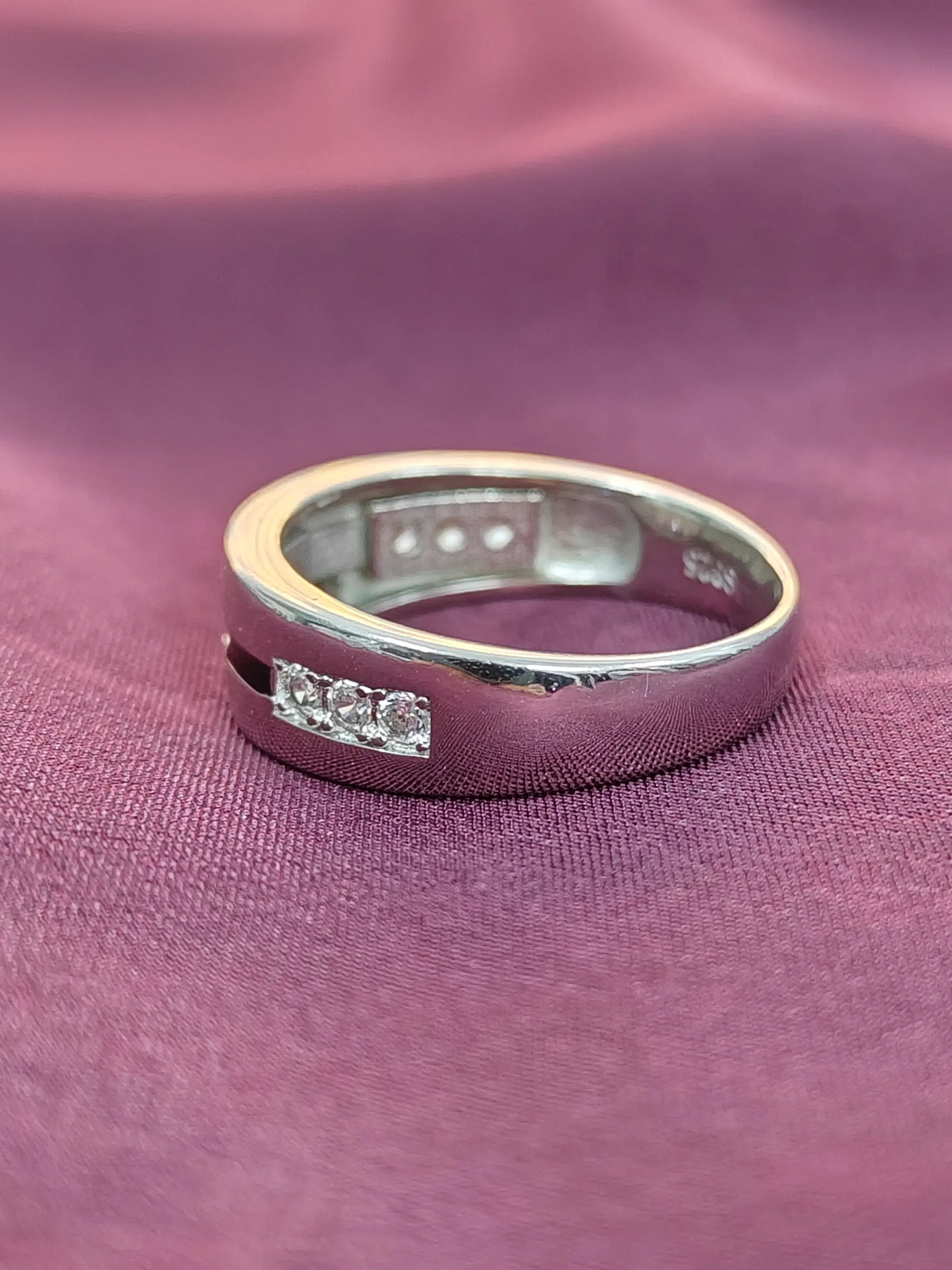 Silver ring with embedded stones on a purple fabric background