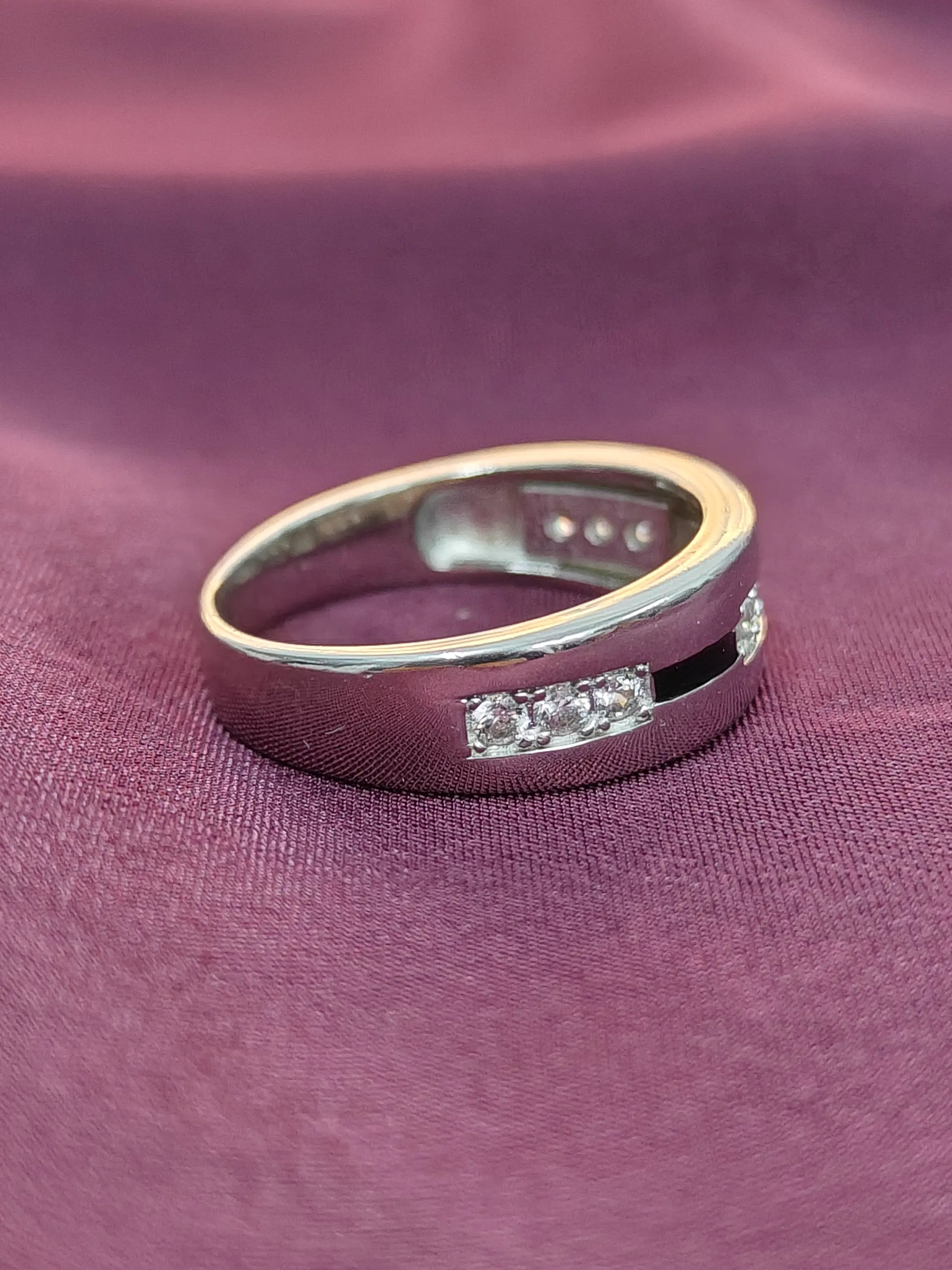 Silver ring with embedded diamonds on a purple fabric background