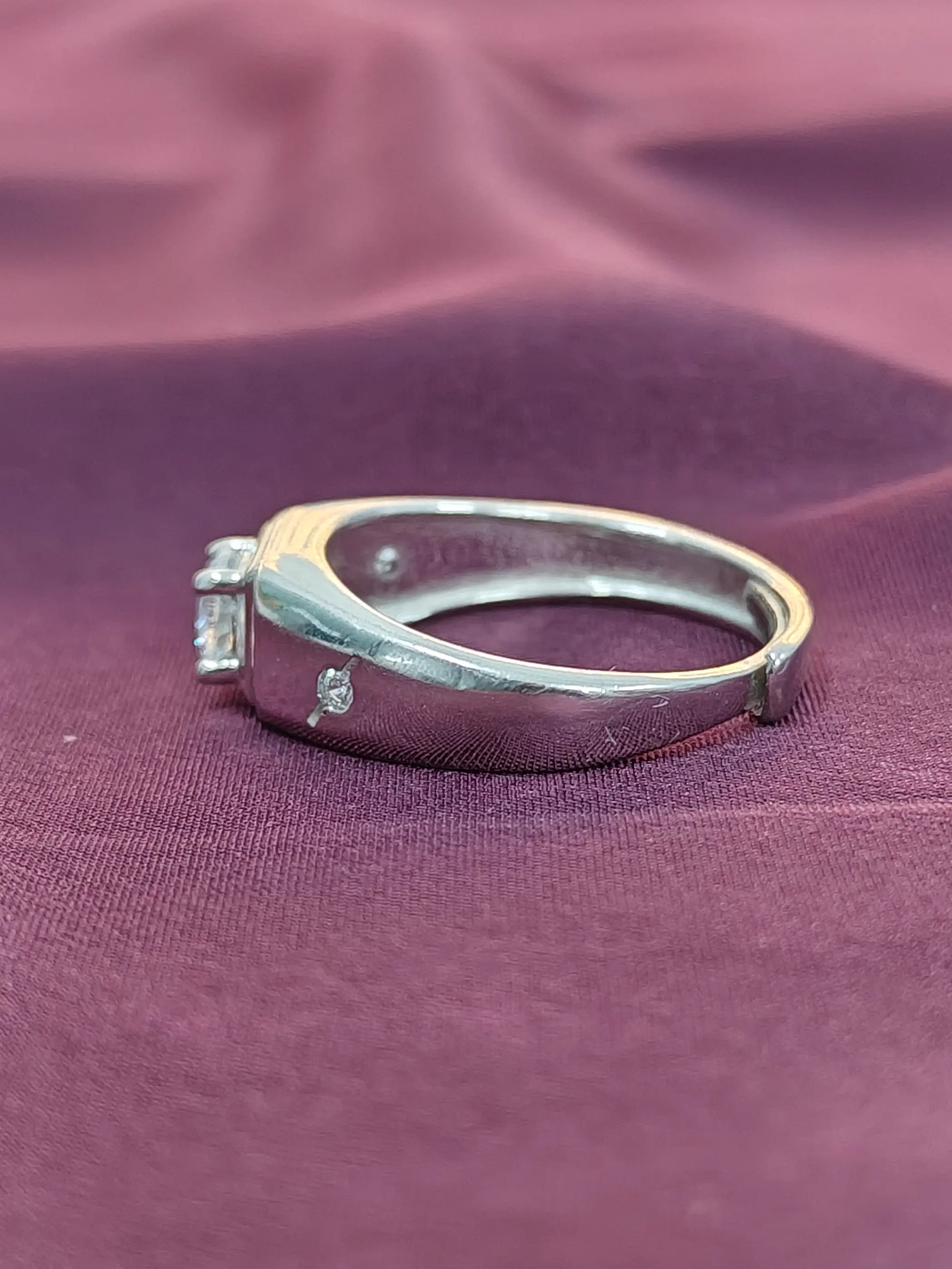 Silver ring with small diamonds on a purple fabric background