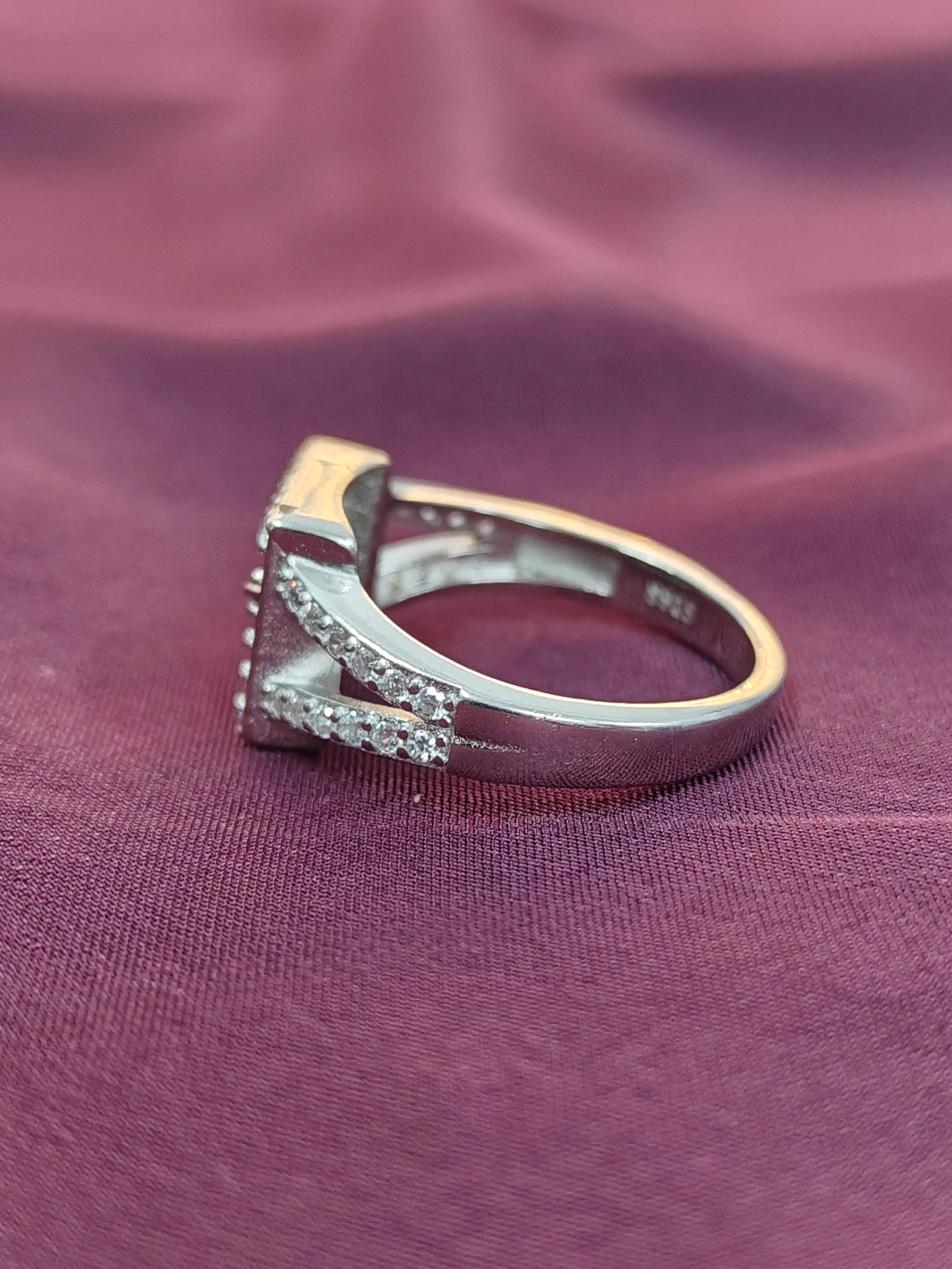 Silver ring with diamonds on a purple fabric background