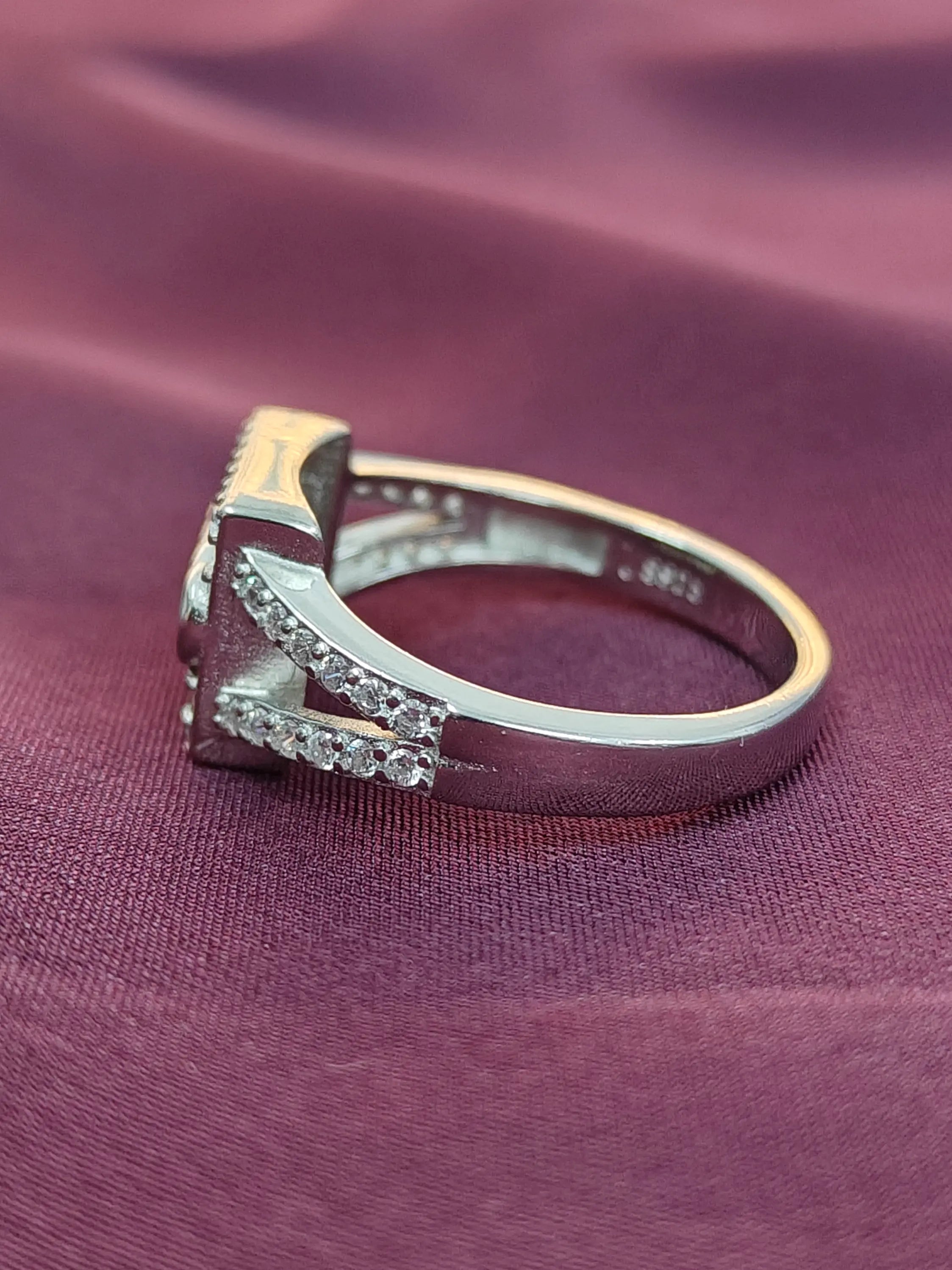 Silver ring with diamonds on a purple fabric background