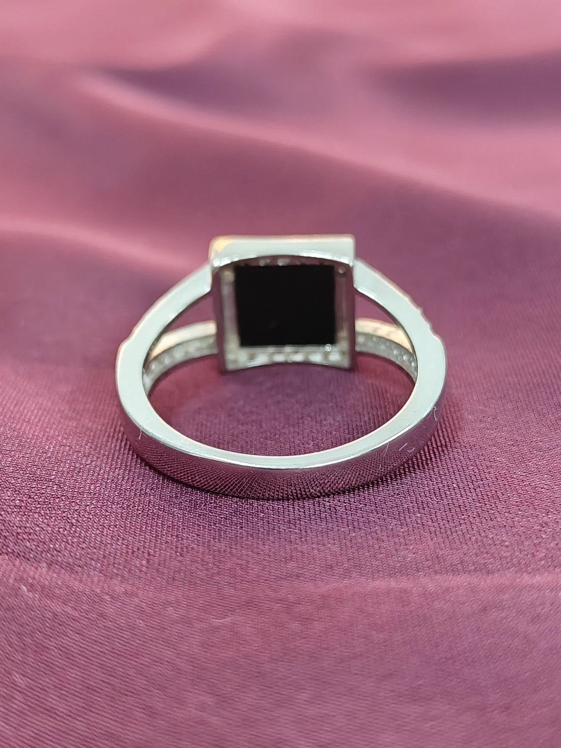 Silver ring with a black gemstone on a pink fabric background