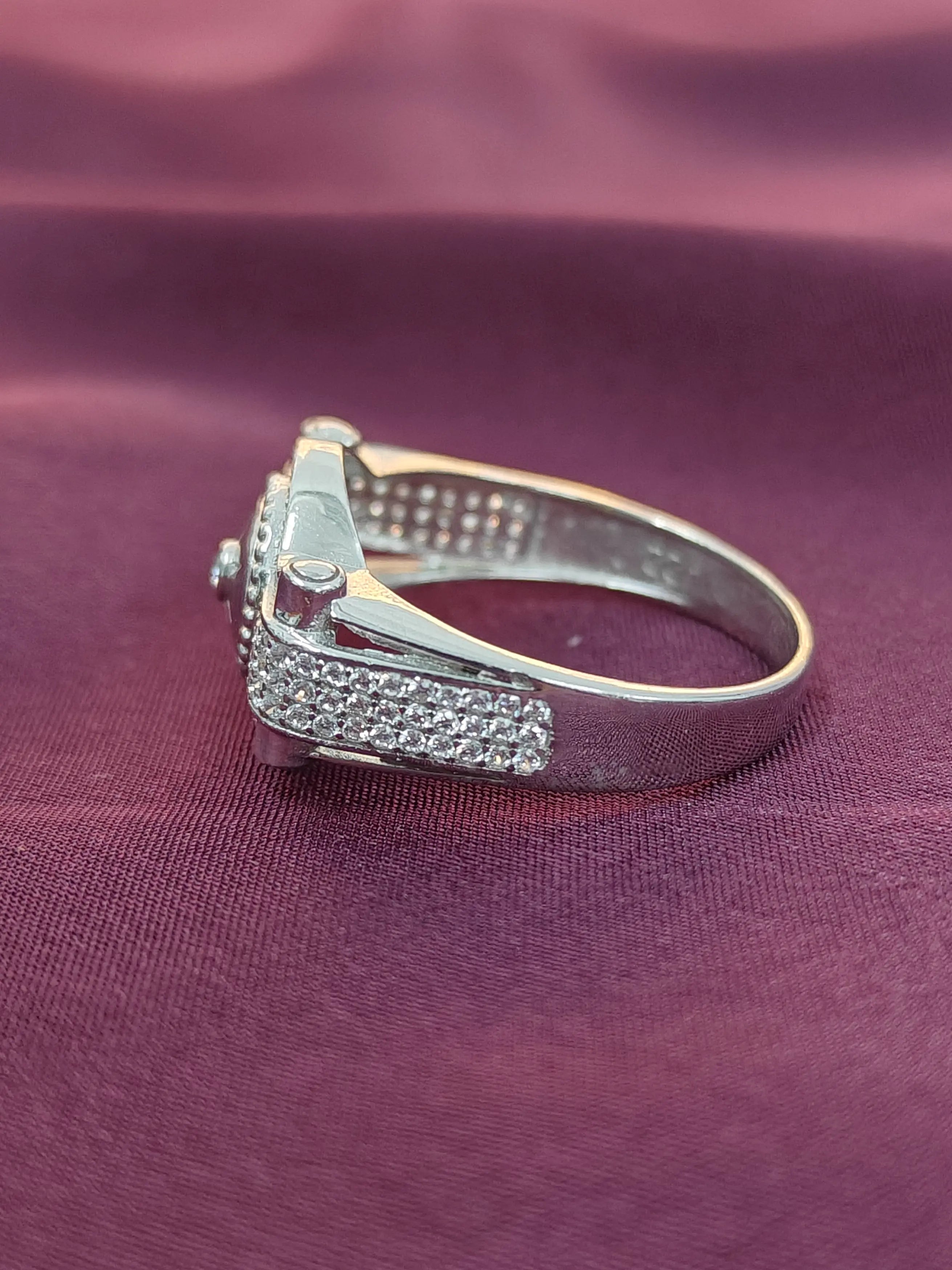Silver ring with a diamond on a purple fabric background