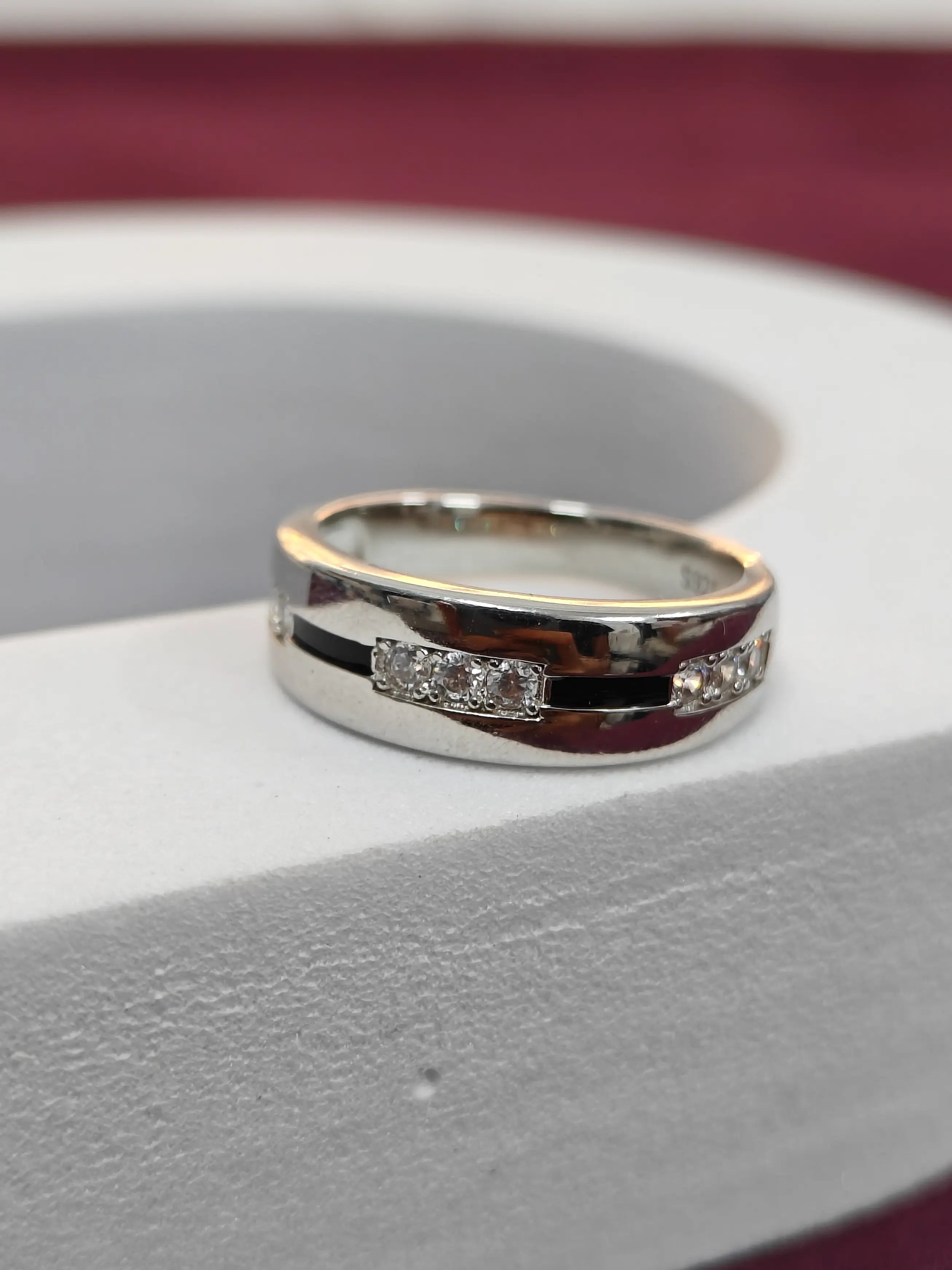 Silver ring with gemstones on a gray surface