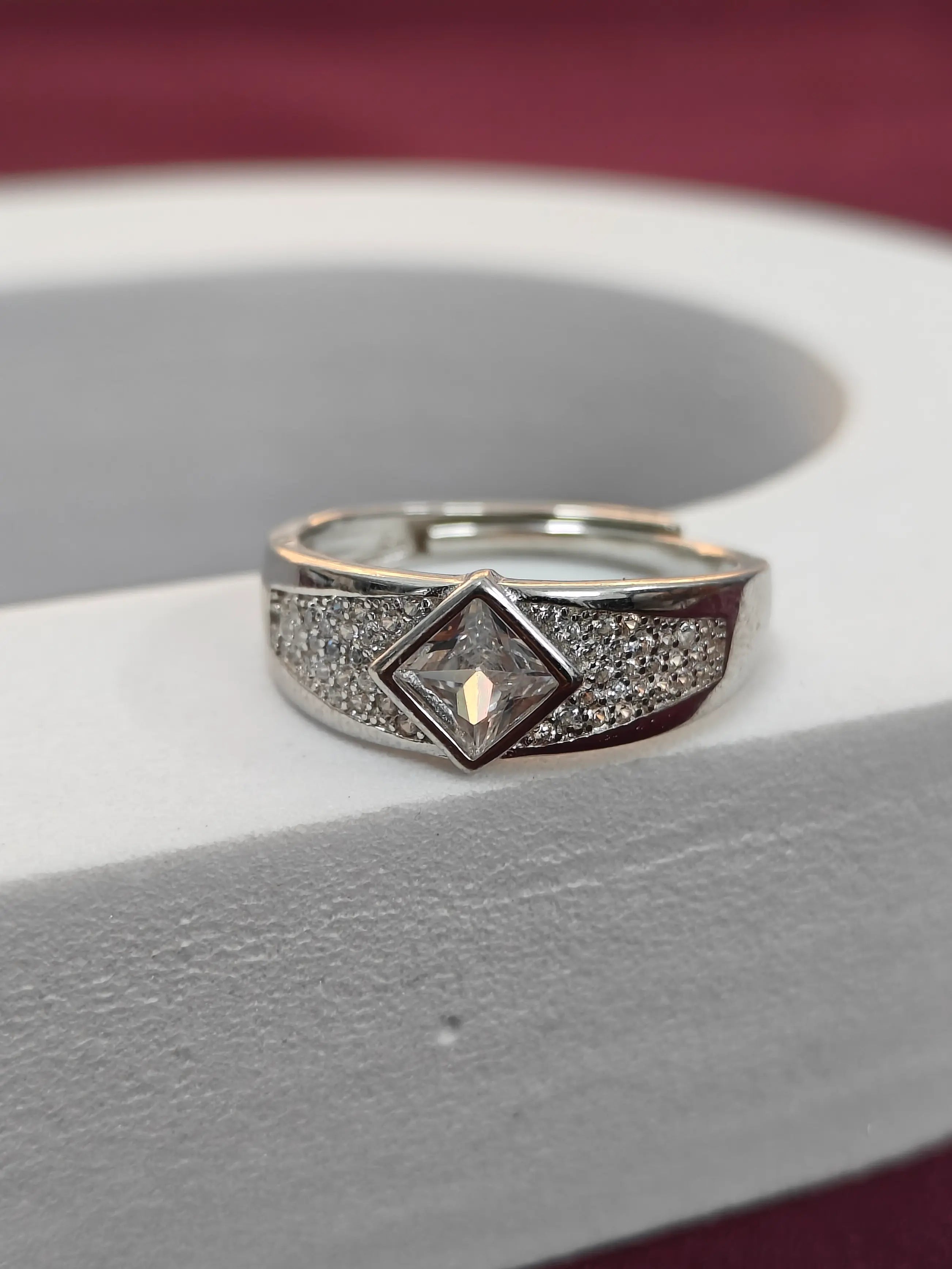 Silver ring with a diamond on a gray surface