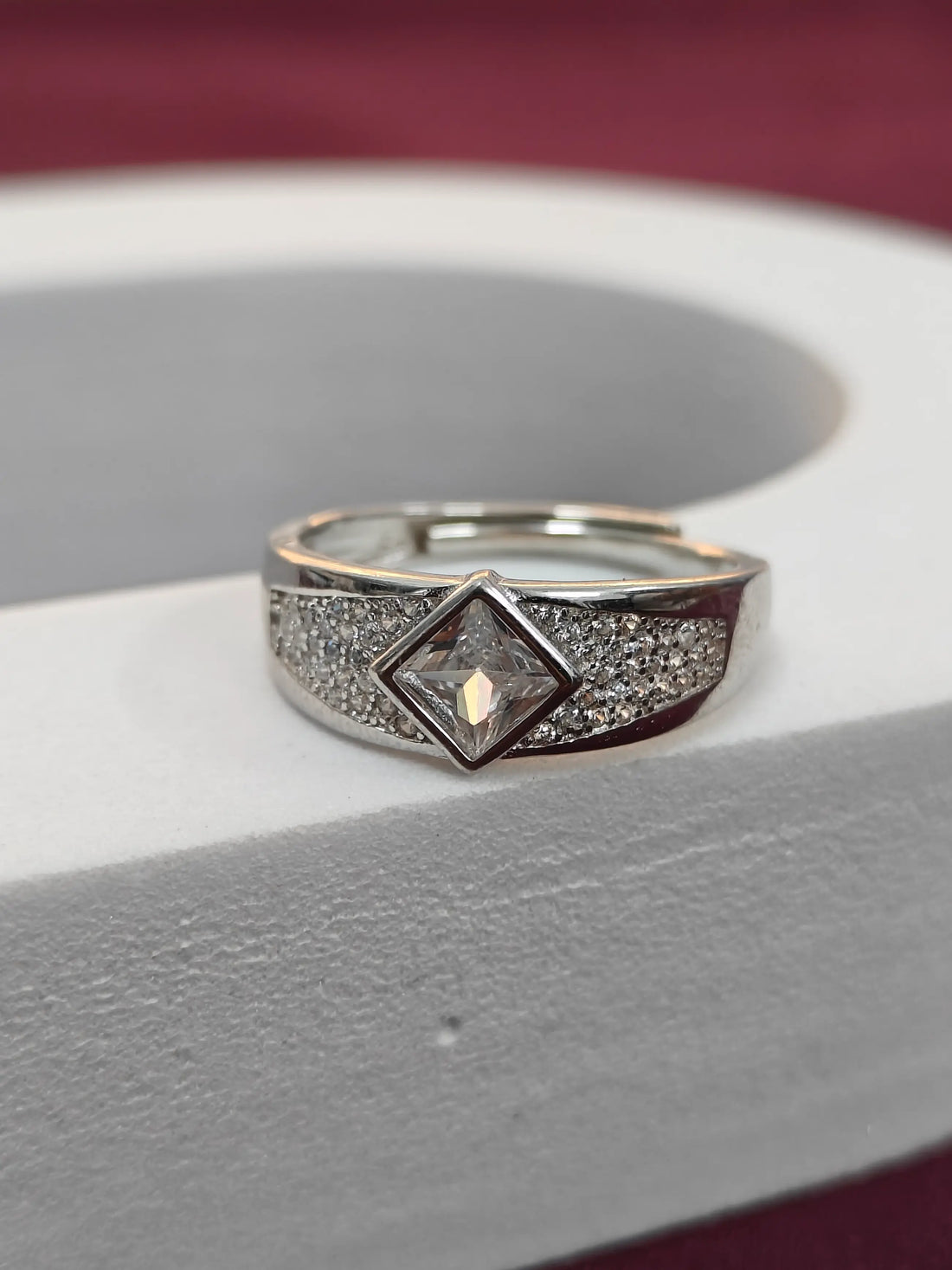 Silver ring with a diamond on a gray surface