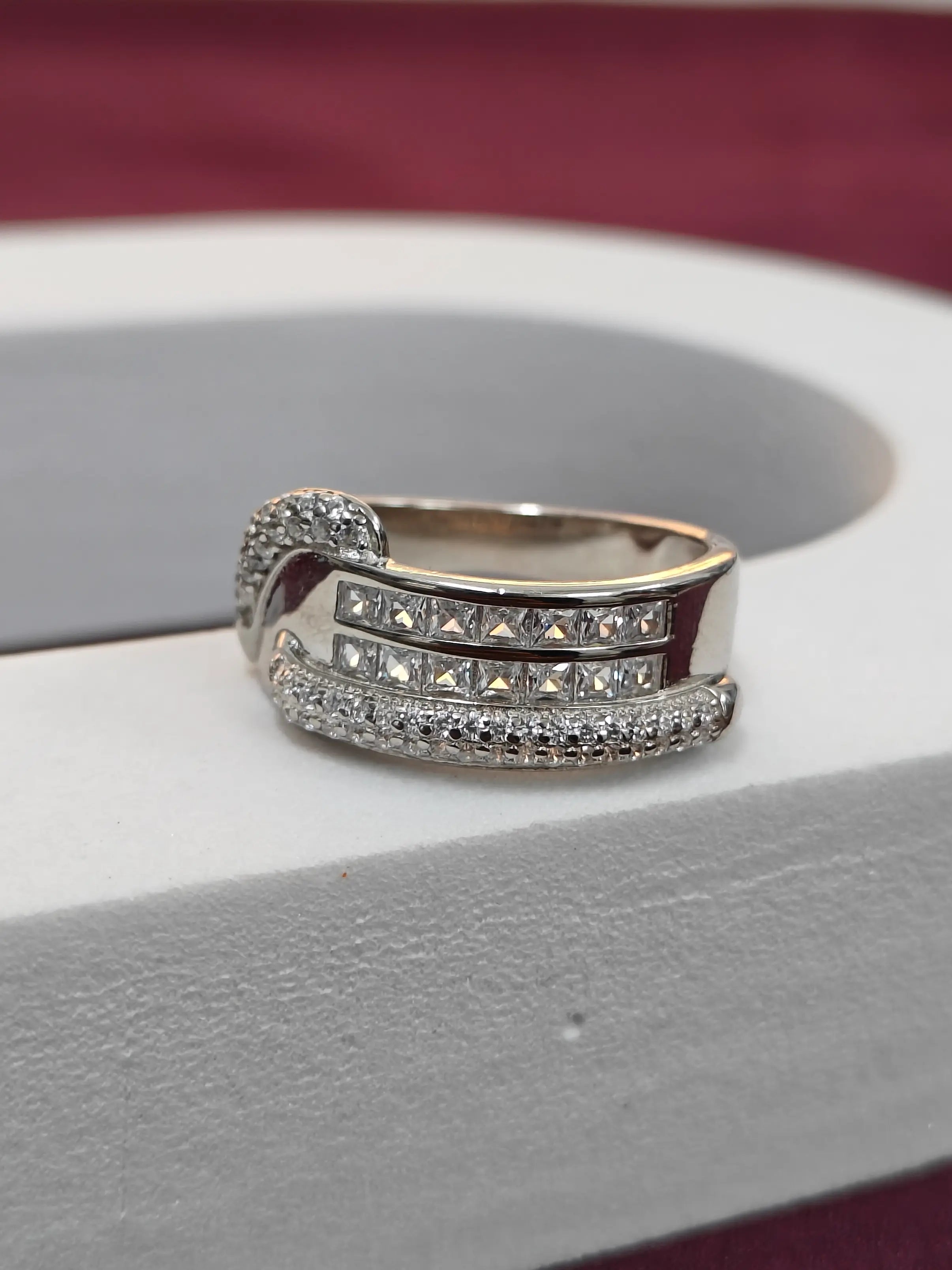 Silver ring with diamond accents on a gray surface