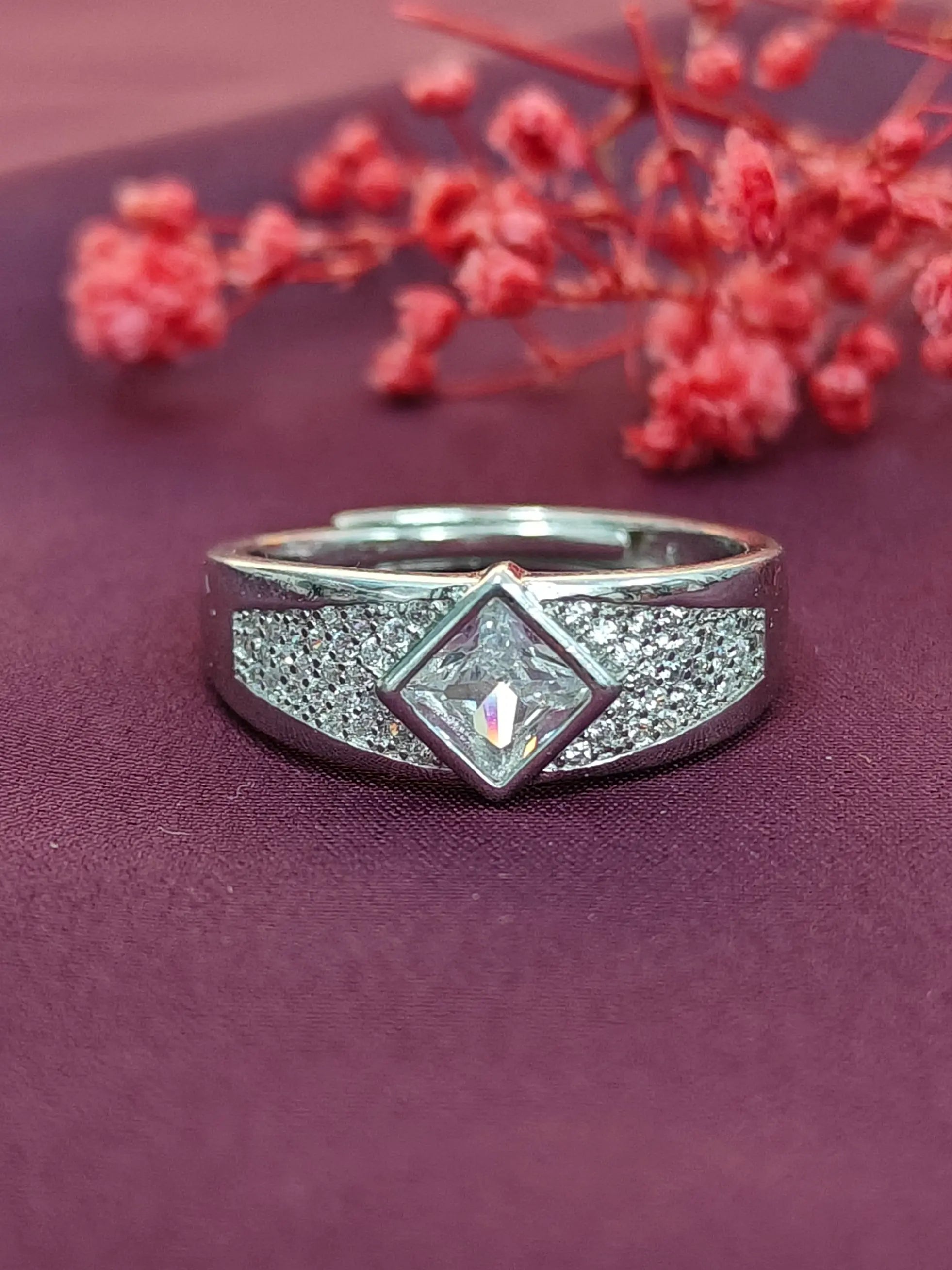Silver ring with gemstone on a purple surface with red flowers
