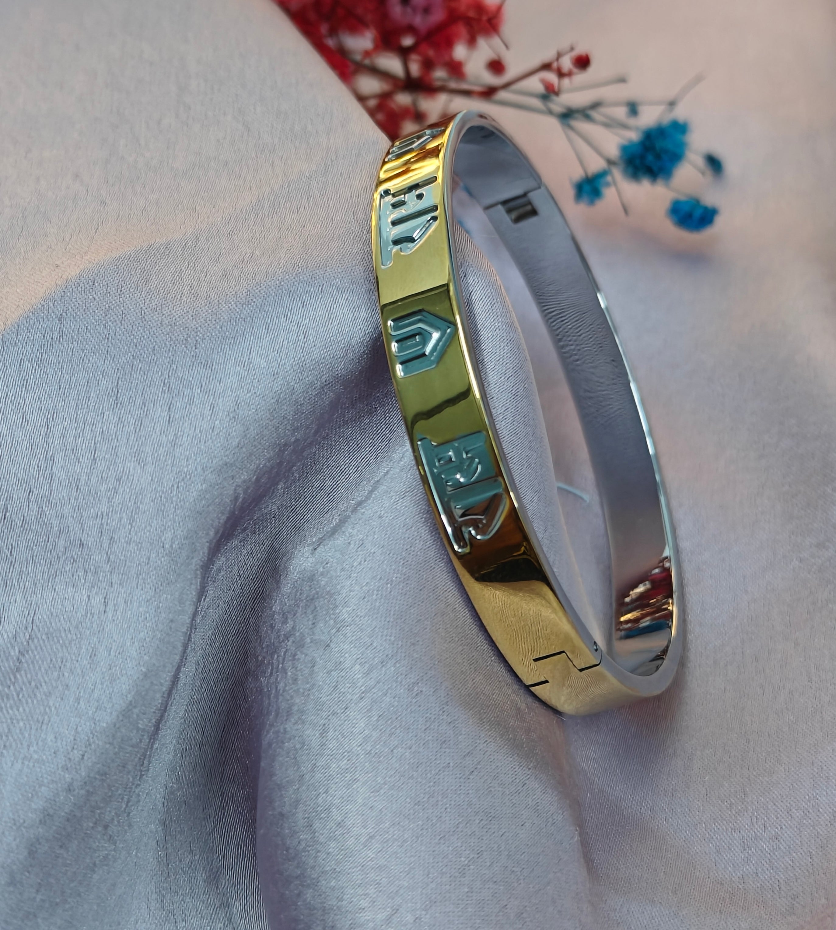 Gold bracelet on a soft fabric background with flowers.