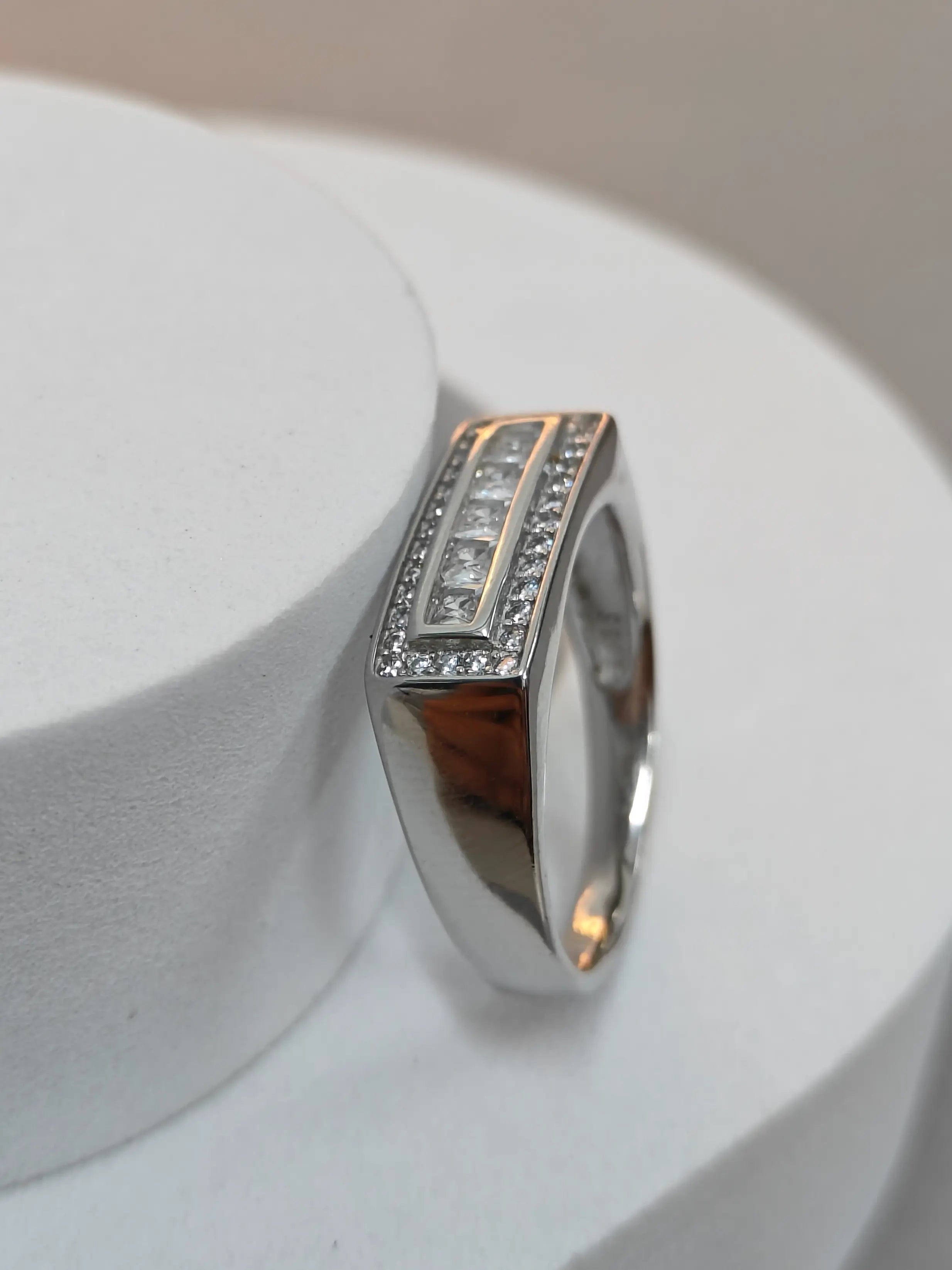 Silver ring with embedded stones on a white stand