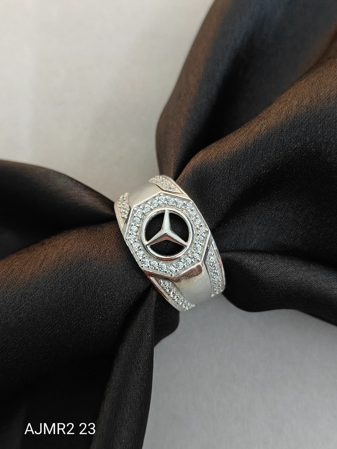 Silver ring with Mercedes-Benz logo on a black fabric background