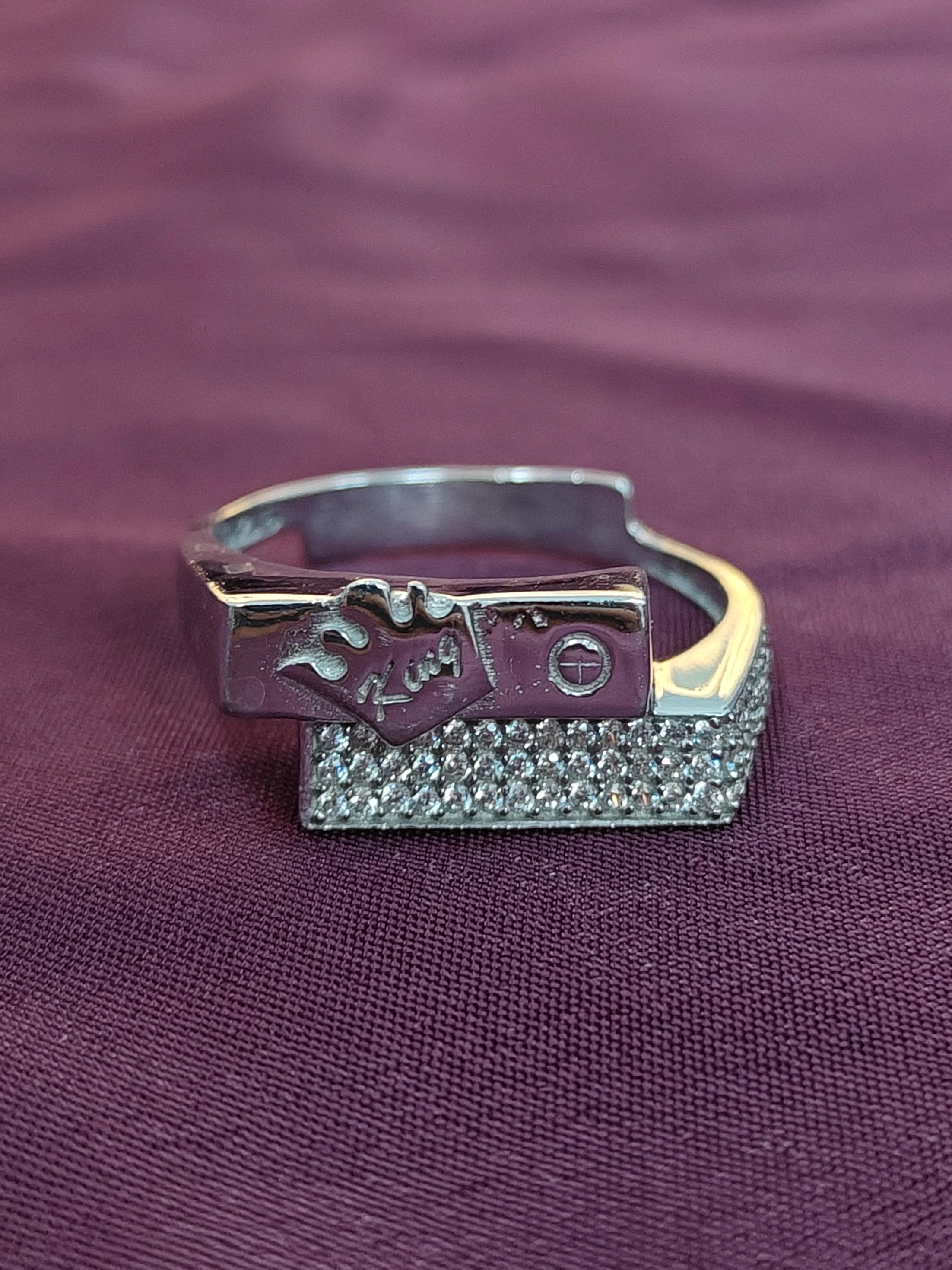 Silver ring with a textured band on a purple fabric background