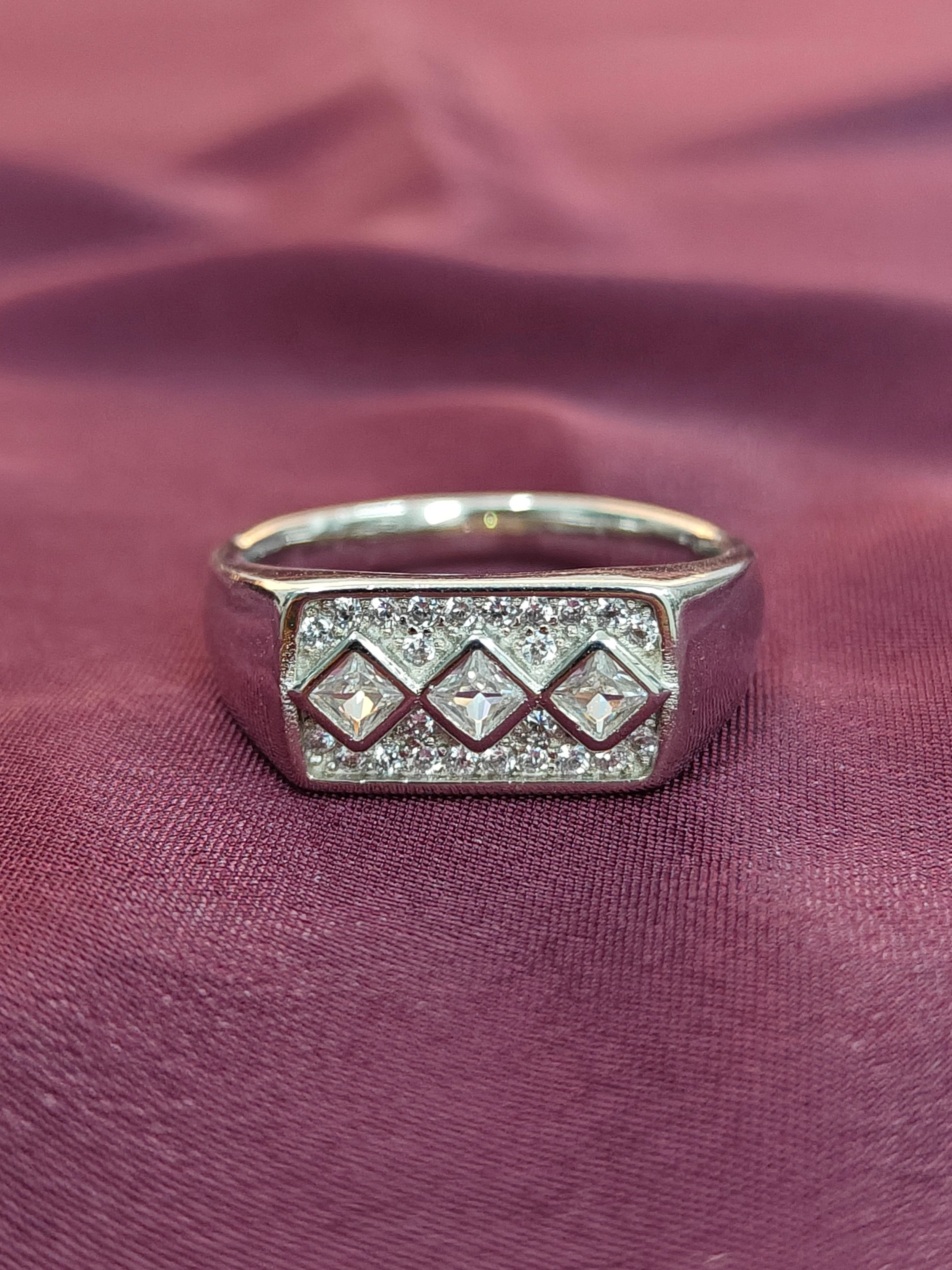 Silver ring with diamond accents on a purple fabric background