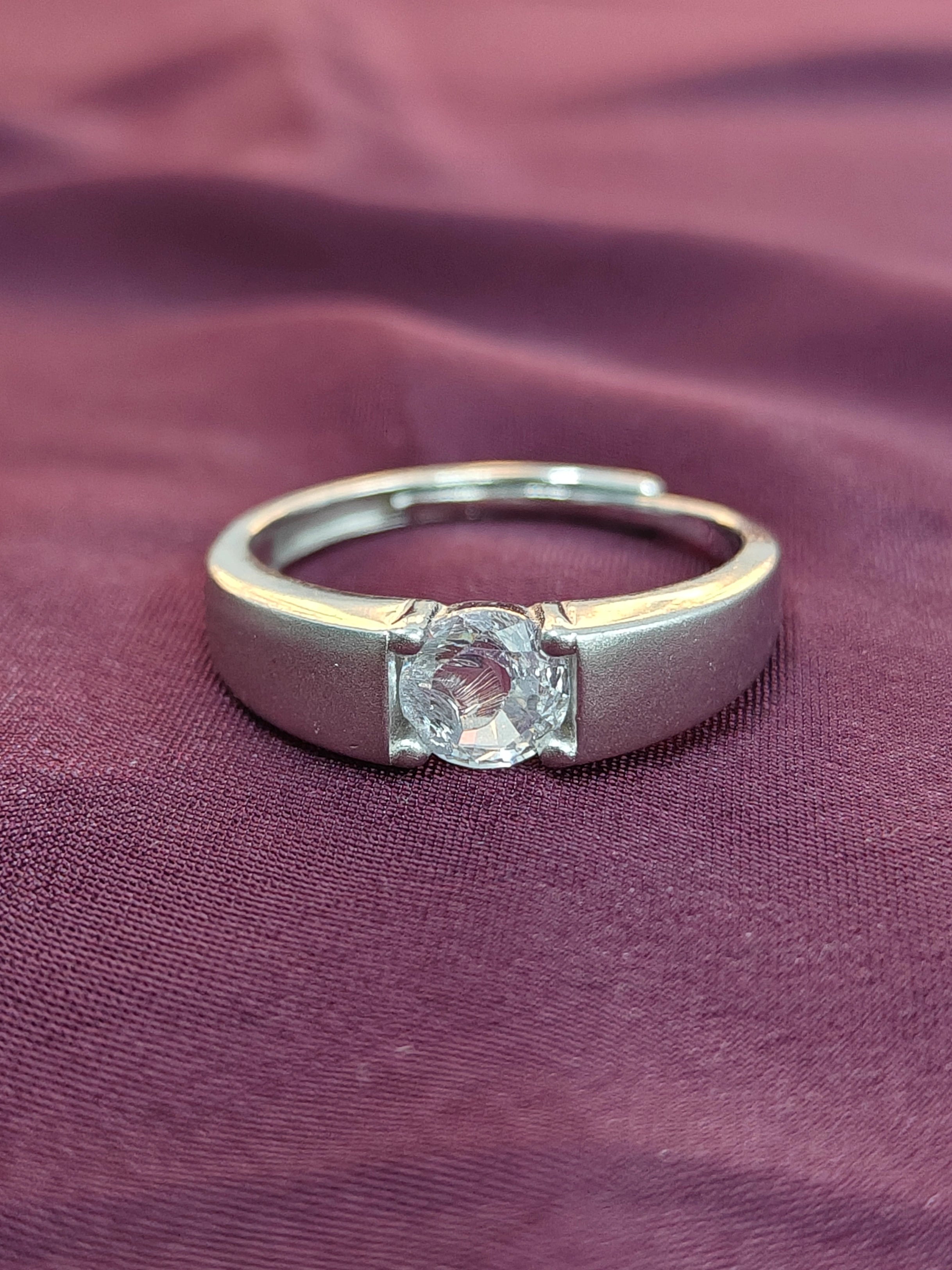 Silver ring with a diamond on a purple fabric background