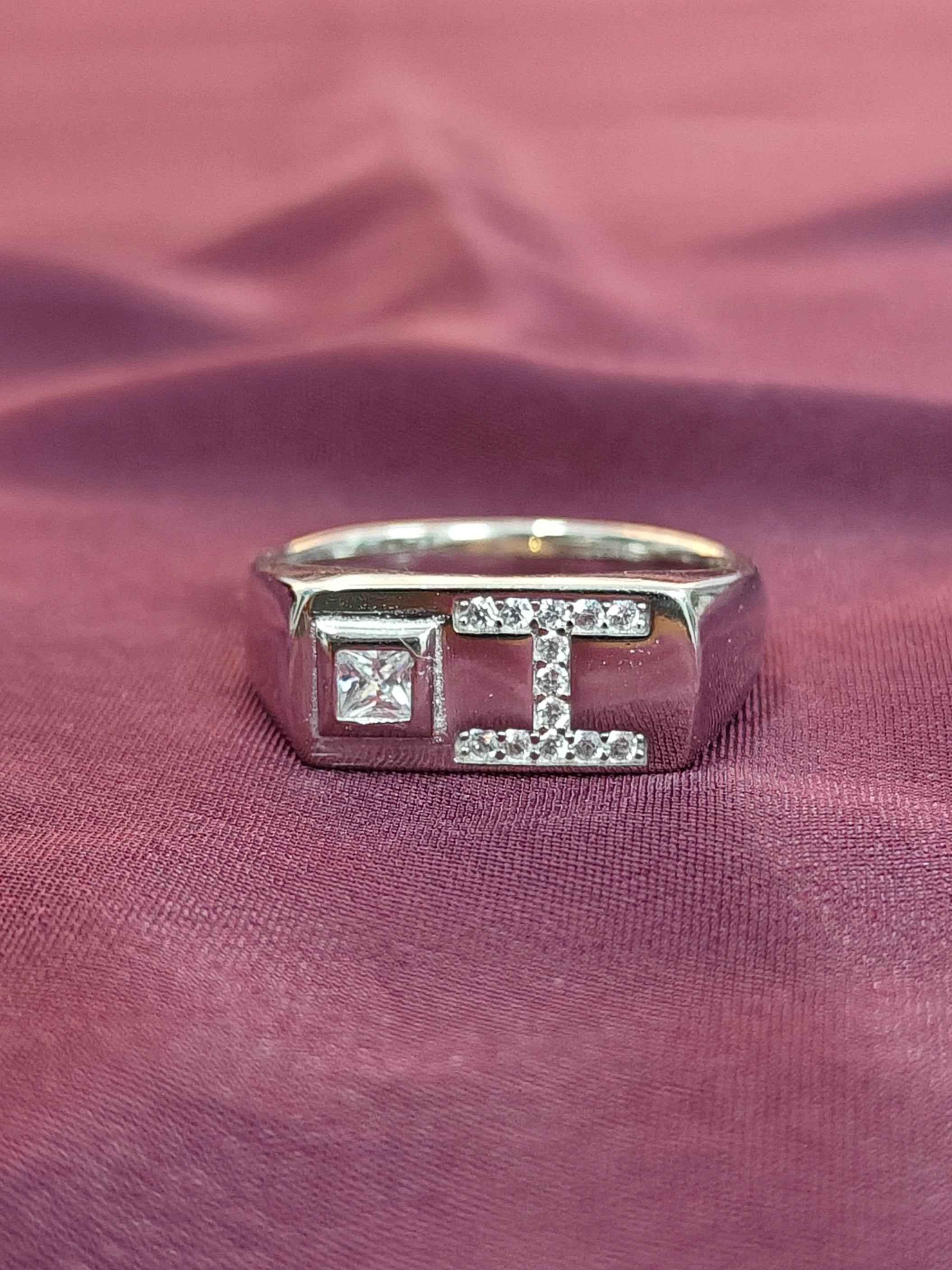 Silver ring with a design on a pink fabric background