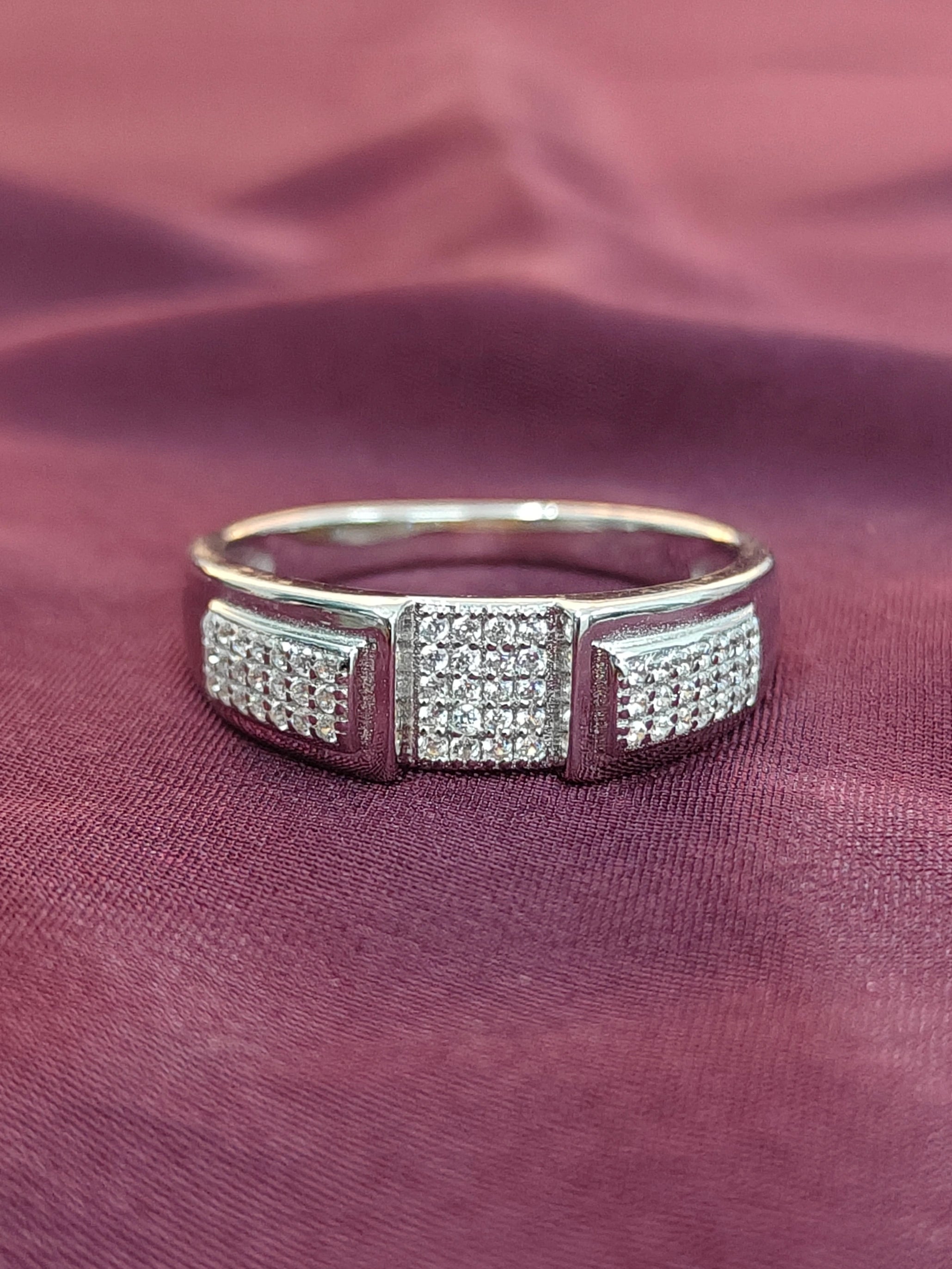 Silver ring with diamond accents on a maroon fabric background
