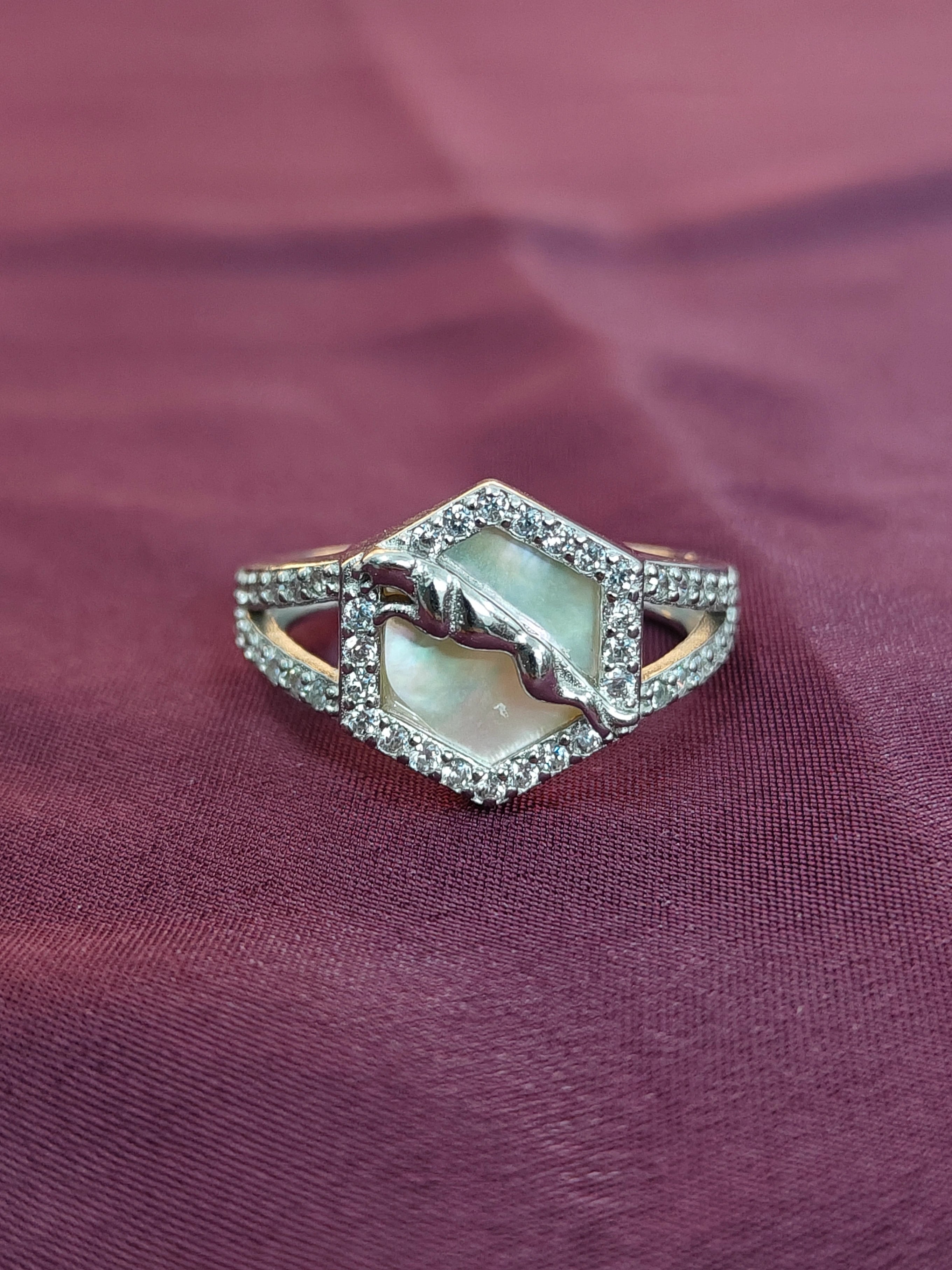 Silver ring with a central gemstone on a purple fabric background