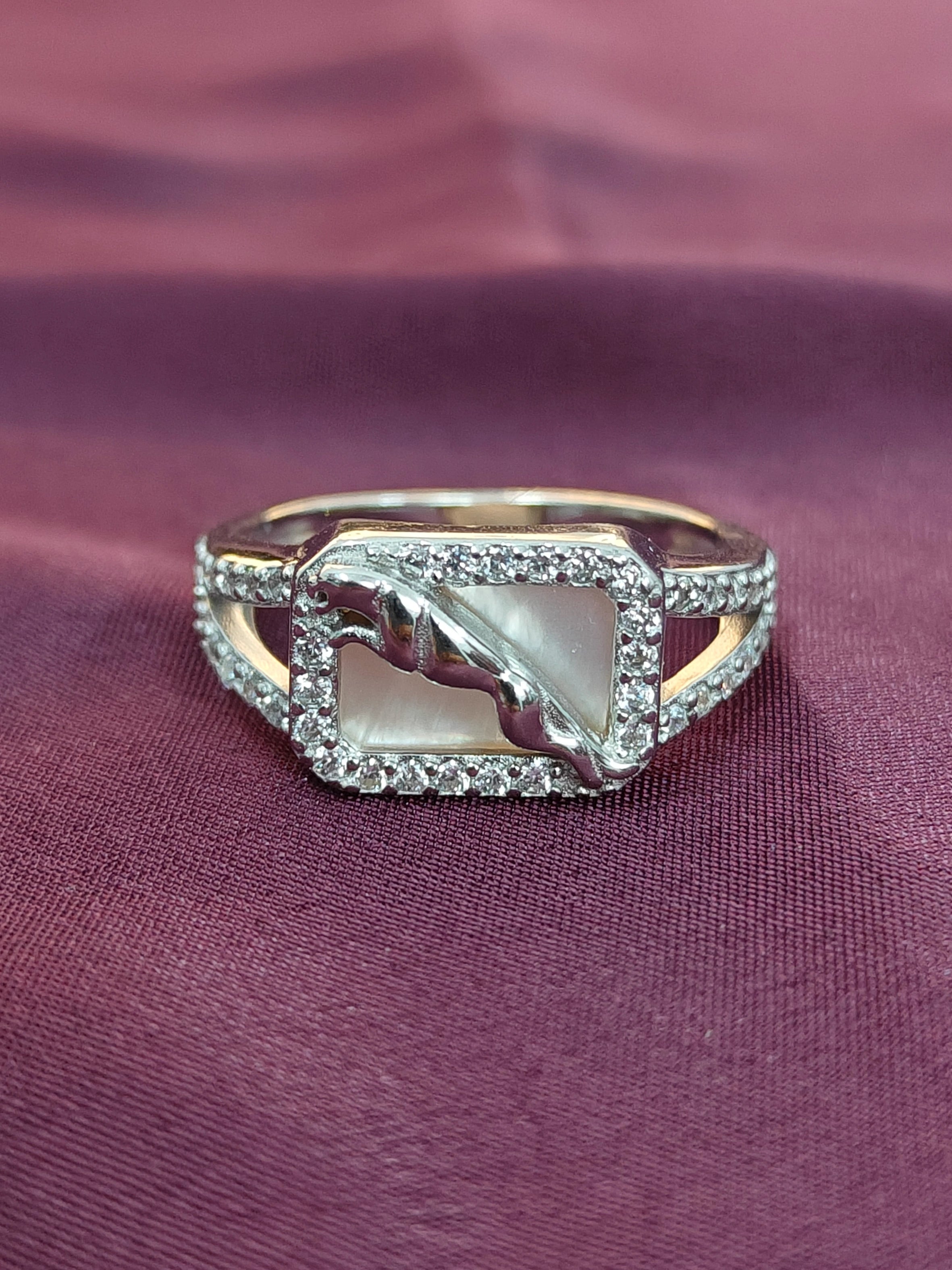 Silver ring with a central stone on a purple fabric background