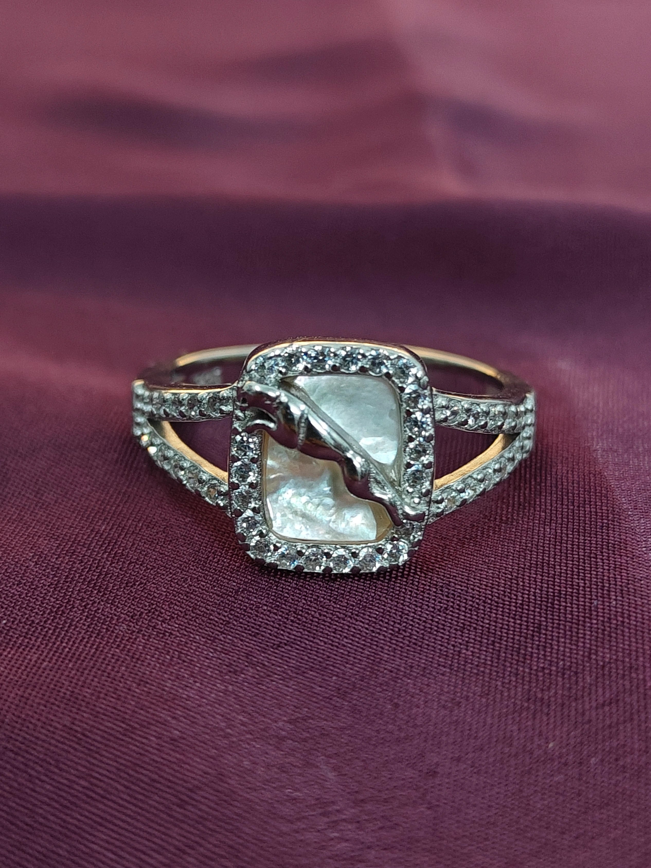 Ring with a central pearl and diamond accents on a purple fabric background